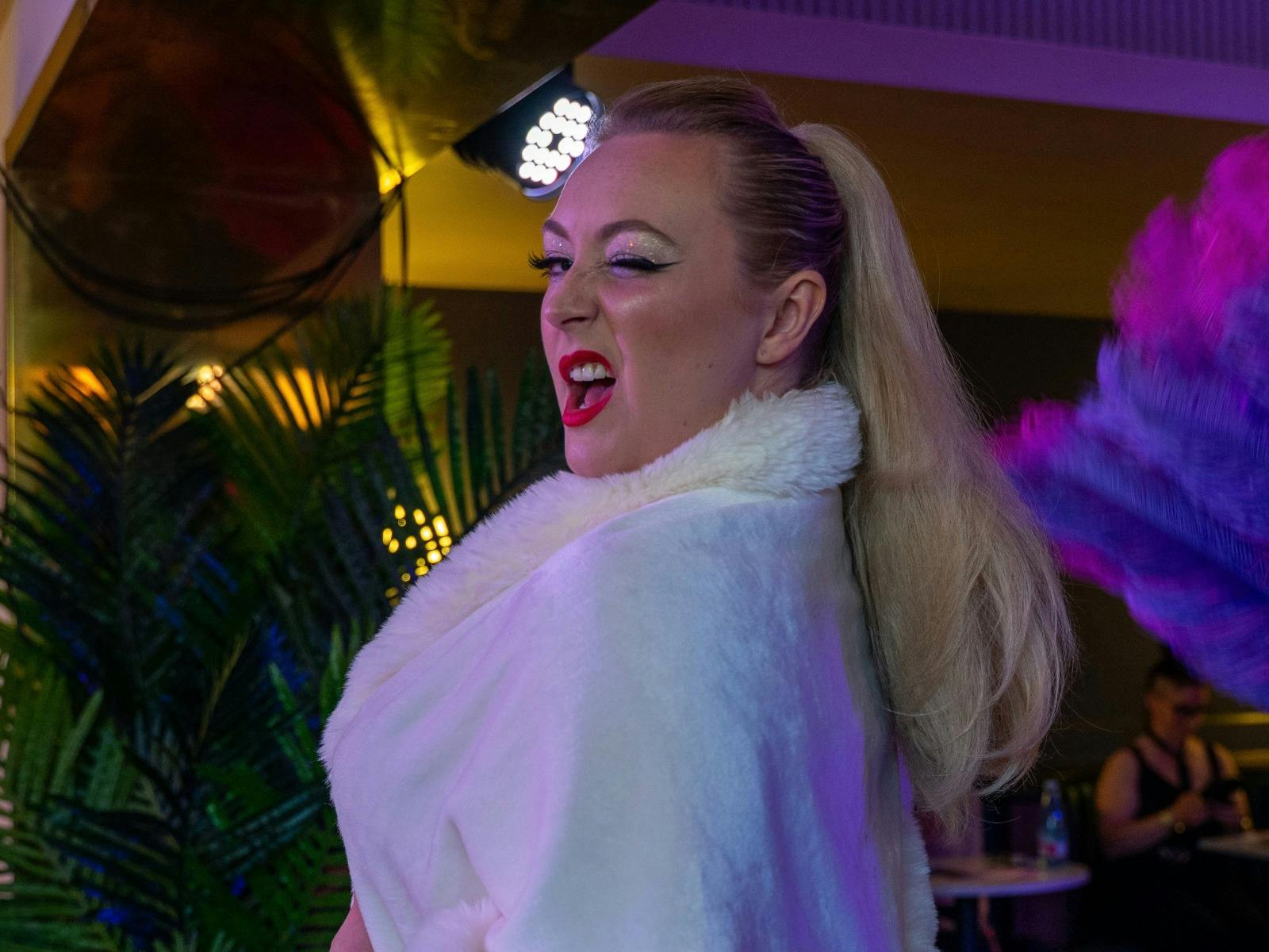 a blonde woman in white winks at camera