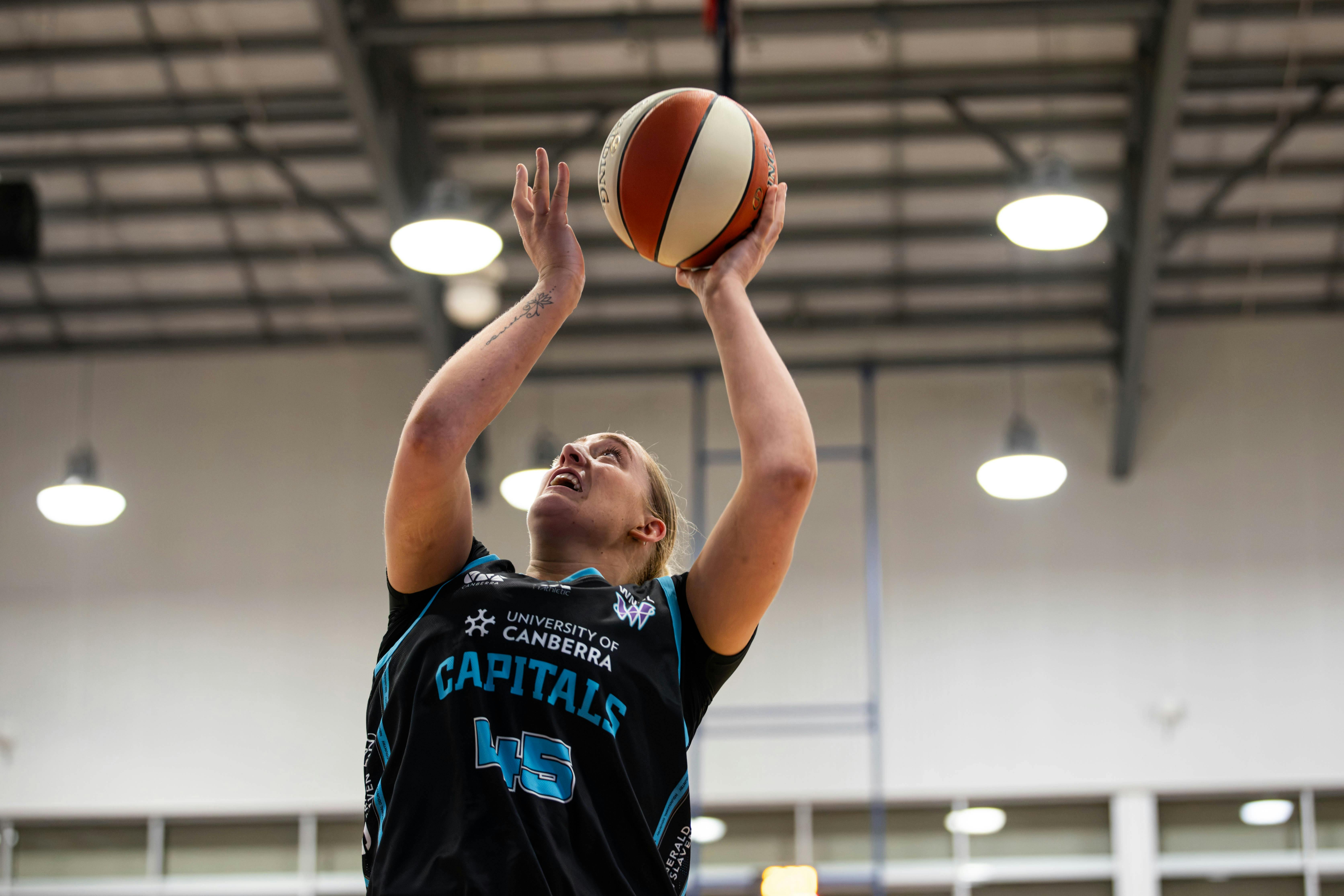 Woman in motion of shooting a basketball.