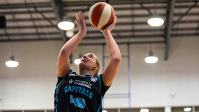 Woman in motion of shooting a basketball.