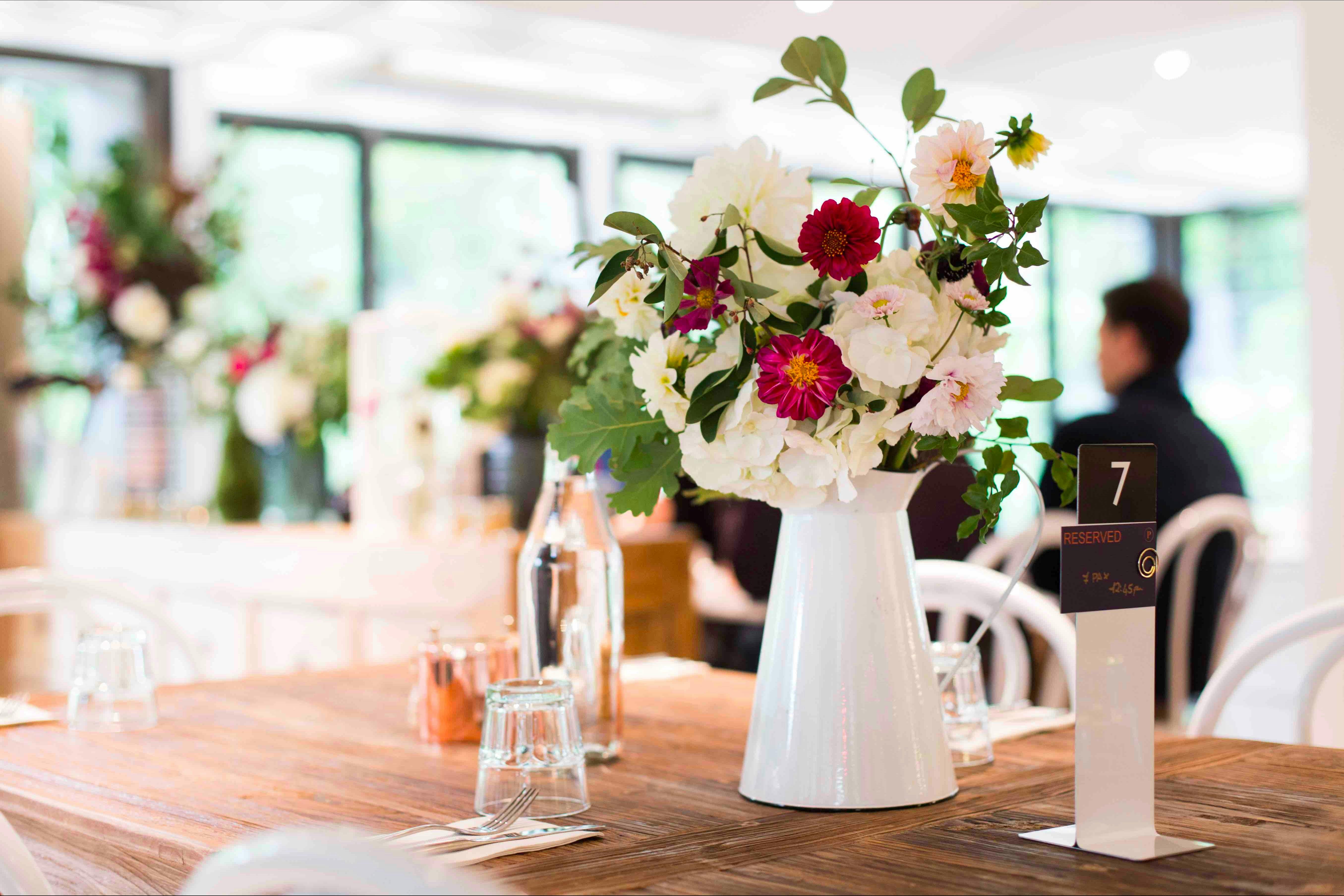 Beautiful white jug filled with fresh flowers on a wooden table