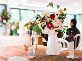 Beautiful white jug filled with fresh flowers on a wooden table