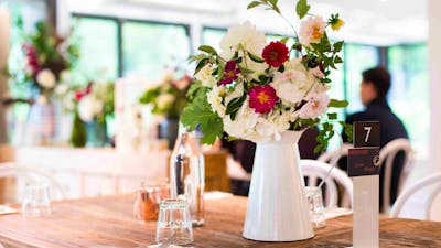 Beautiful white jug filled with fresh flowers on a wooden table