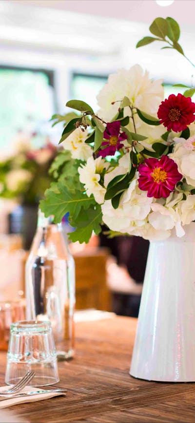 Beautiful white jug filled with fresh flowers on a wooden table