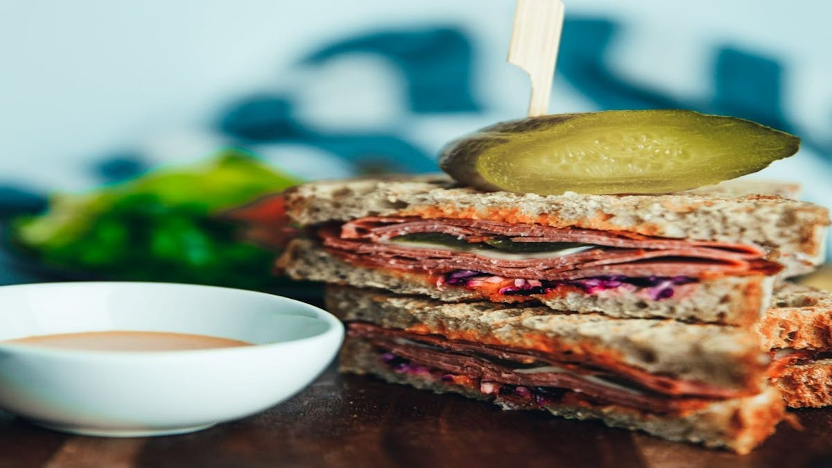 Picnic Society's Signature Sandwich with homemade pickles, shaved corn beef, bitey cheese and salad