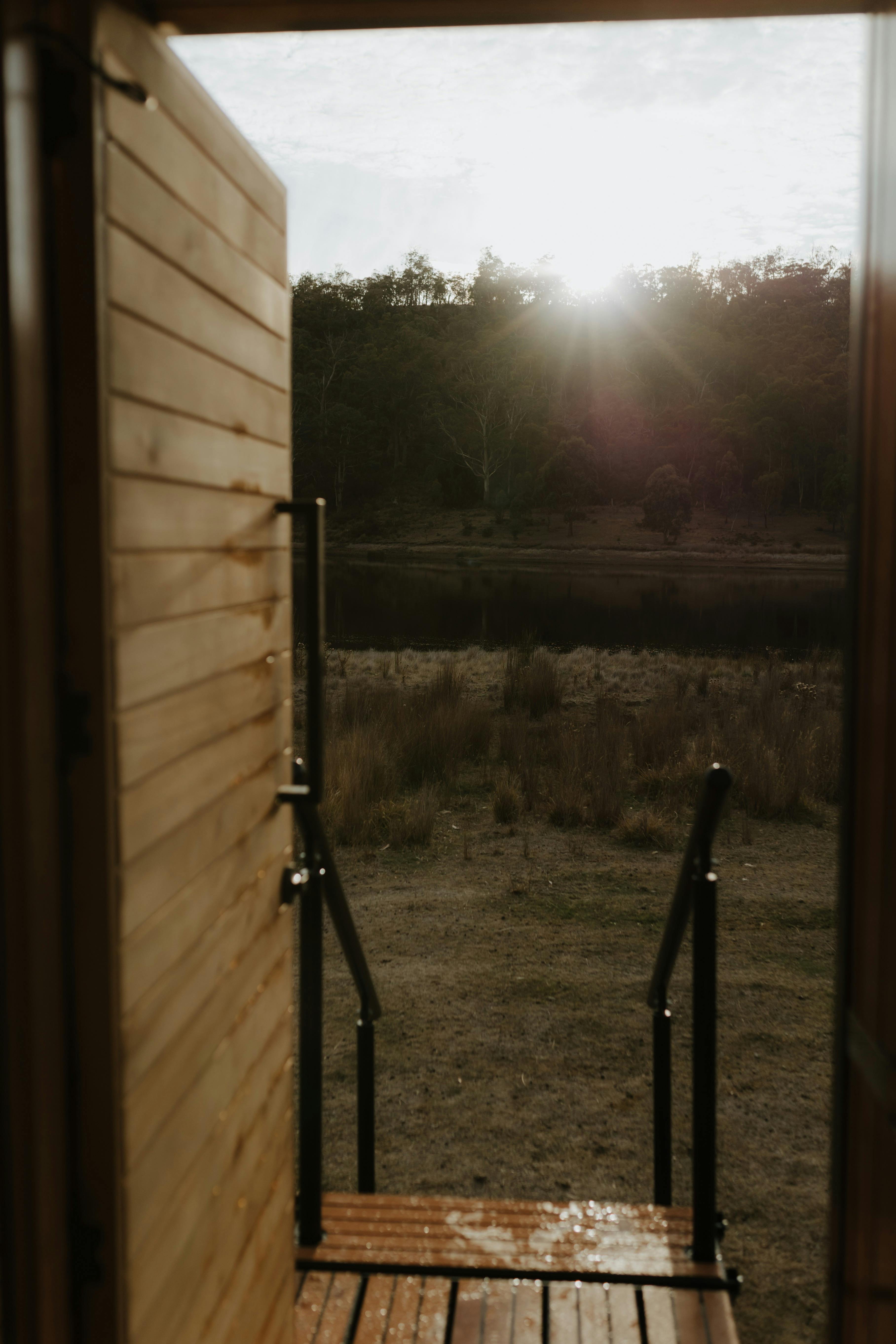 View from a sauna doorway overlooking a river, grassland and native forest.