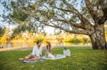A young couple enjoying a picnic under a large tree along the riverside