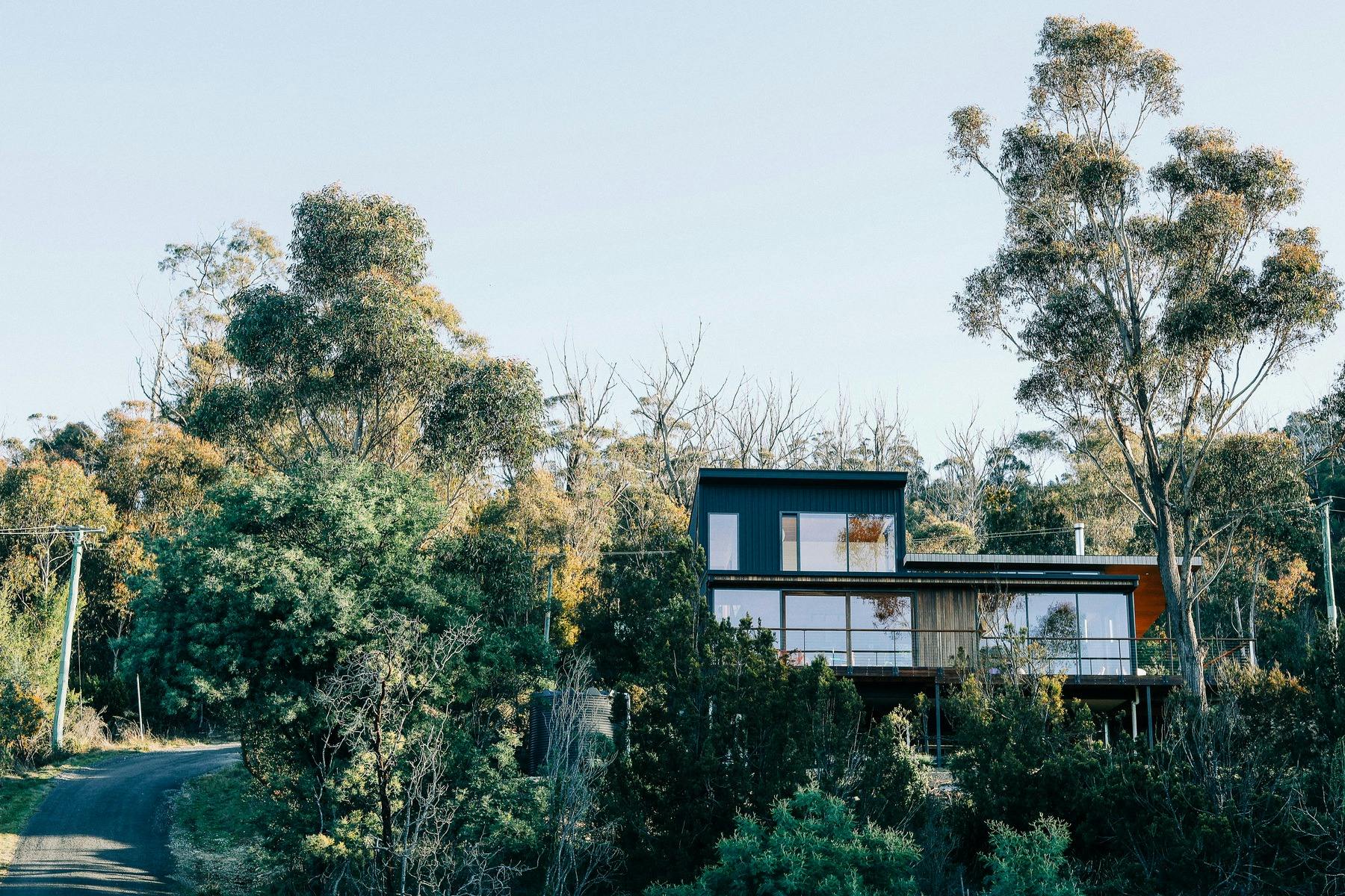 A picture of a two story contemporary modern house from the front, nestled in the Australian bush