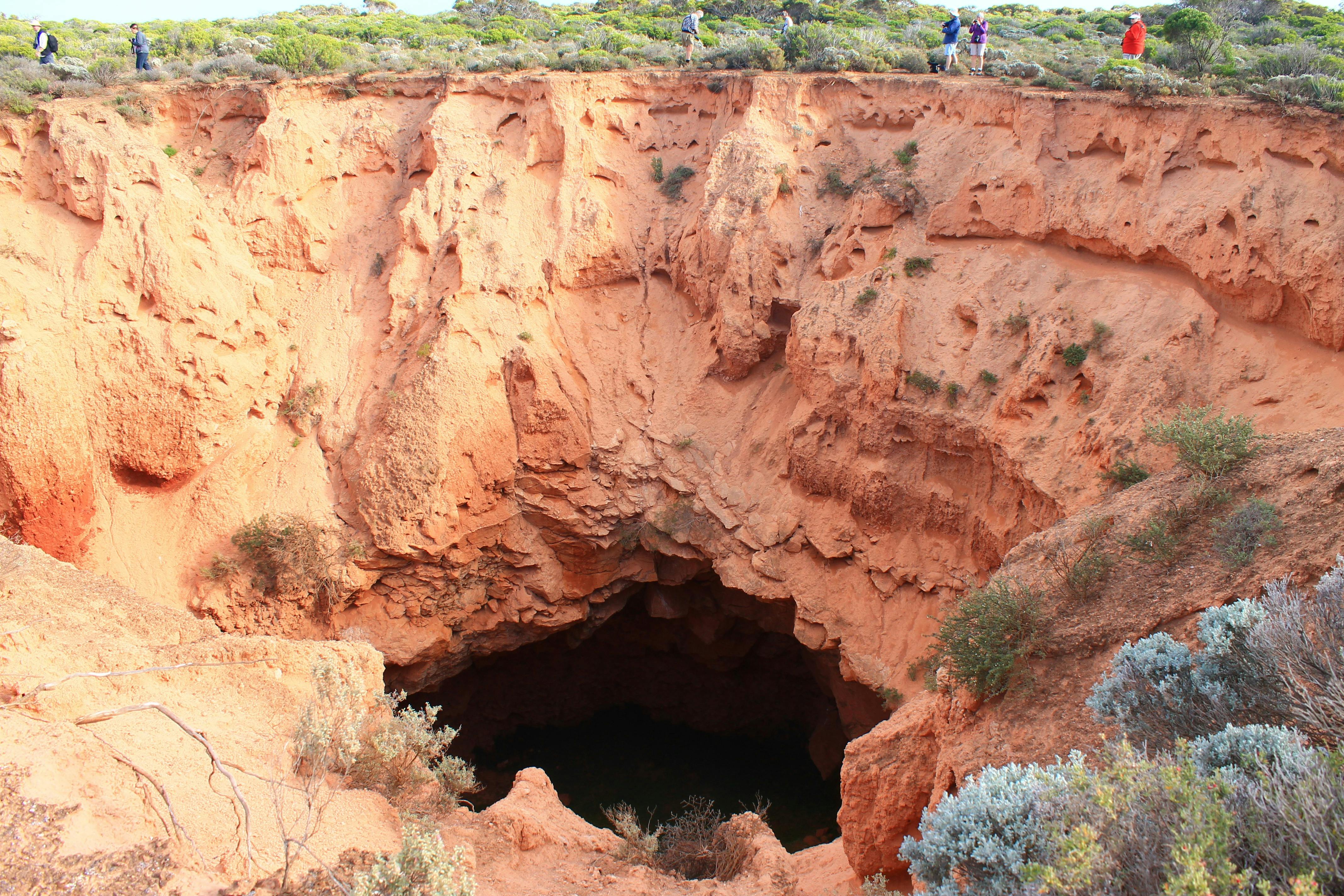 The drop into a cave with people walking around the rim