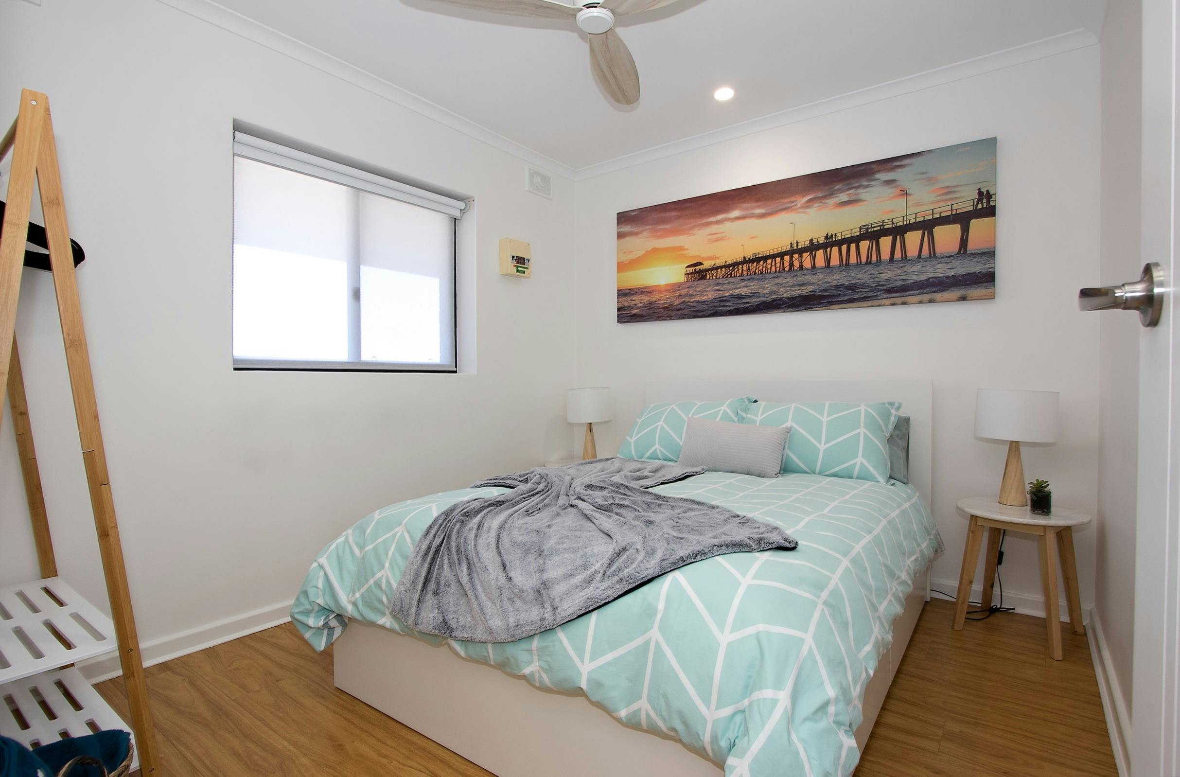 2nd bedroom with a double bed, side tables, bedside lamps, garment rack and a city view