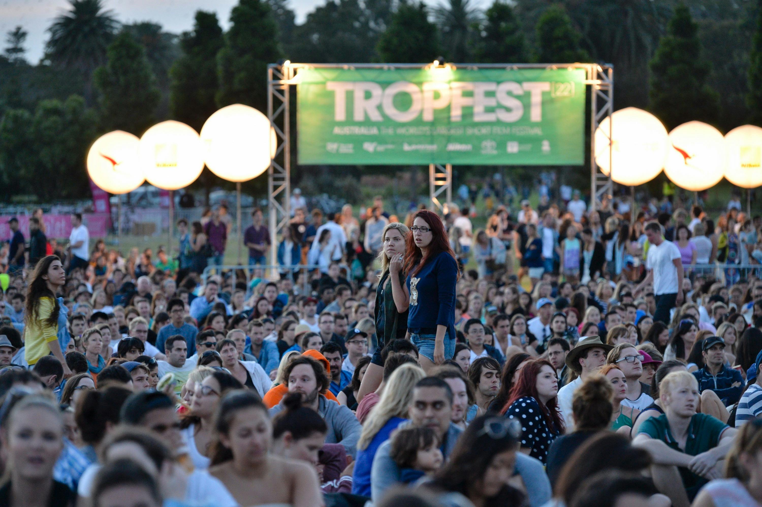 A large gathering of people is watching the Tropfest screen with Tropfest branding in background