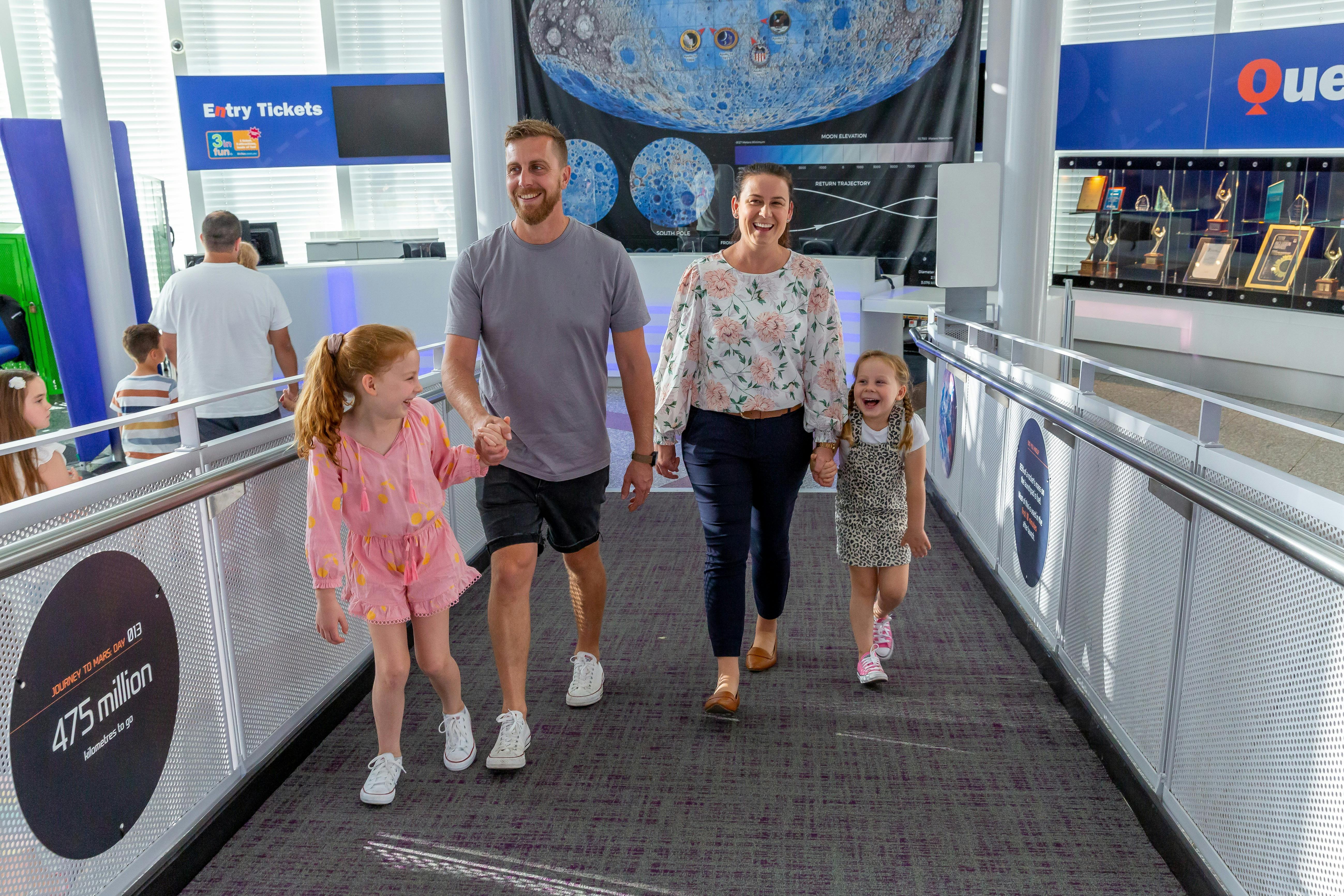 family of 4 walk up the Questacon ramp by the ticket desk