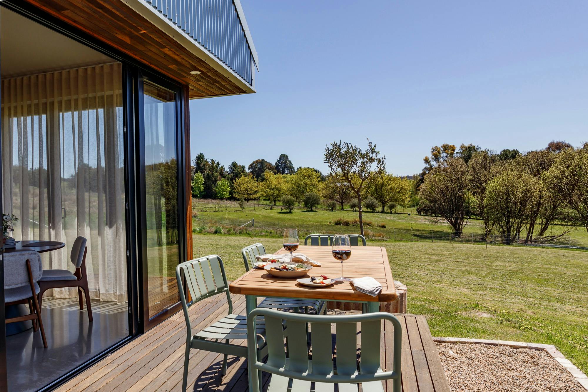Outdoor deck, paddock in background and dining table set for snacks and wine