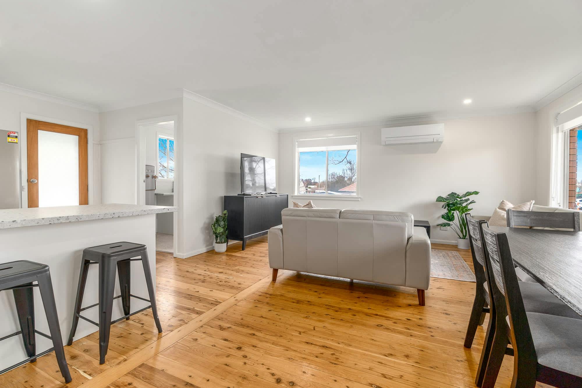Large living area with couch, tv, bar stools at the kitchen bench and dining table at 43 orange rd