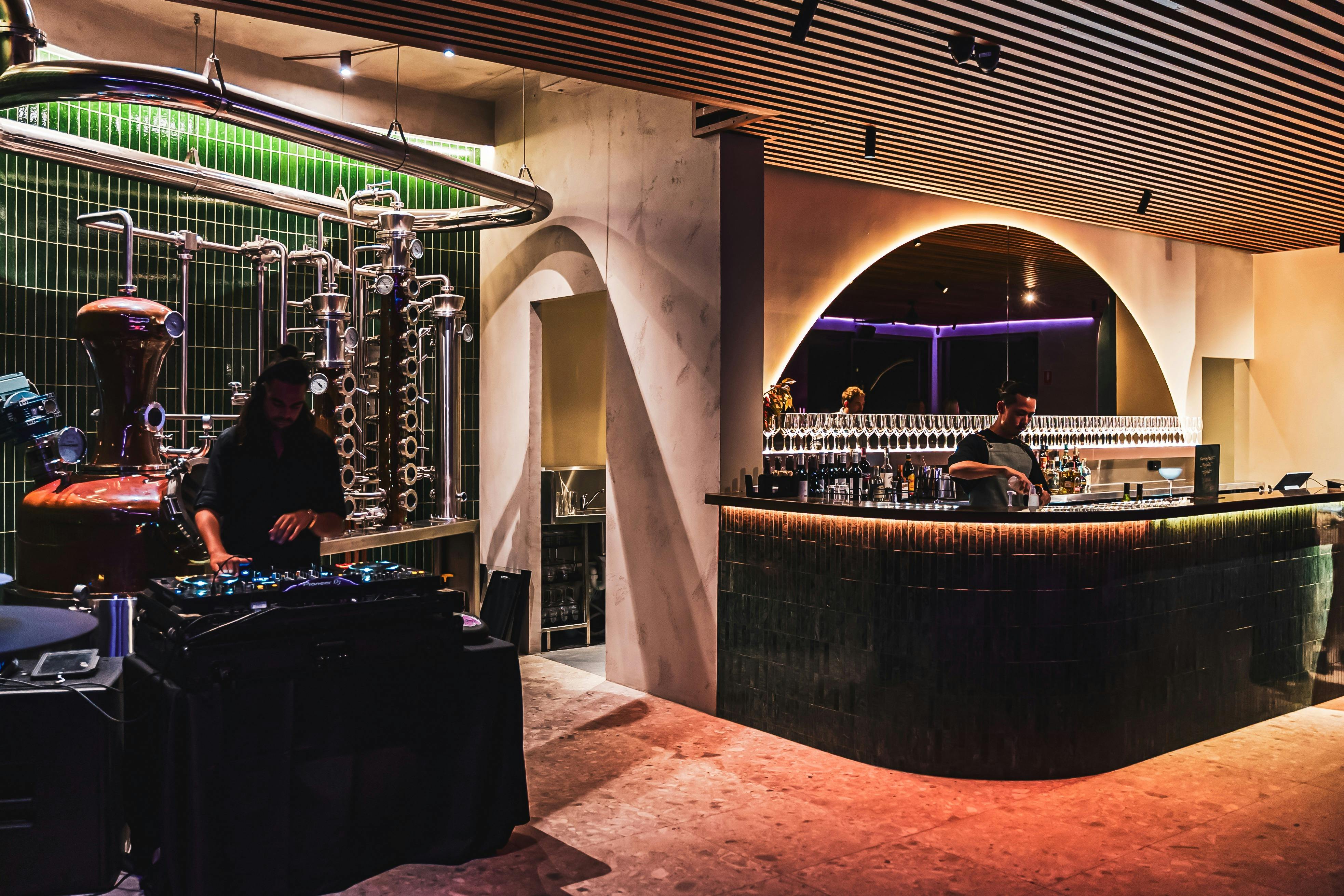 A DJ set up in front of the 74 Islands Distillery still plays tunes, a bartender prepares a drink