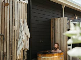 Outdoor timber bath set within timber privacy screens beside a holiday home.