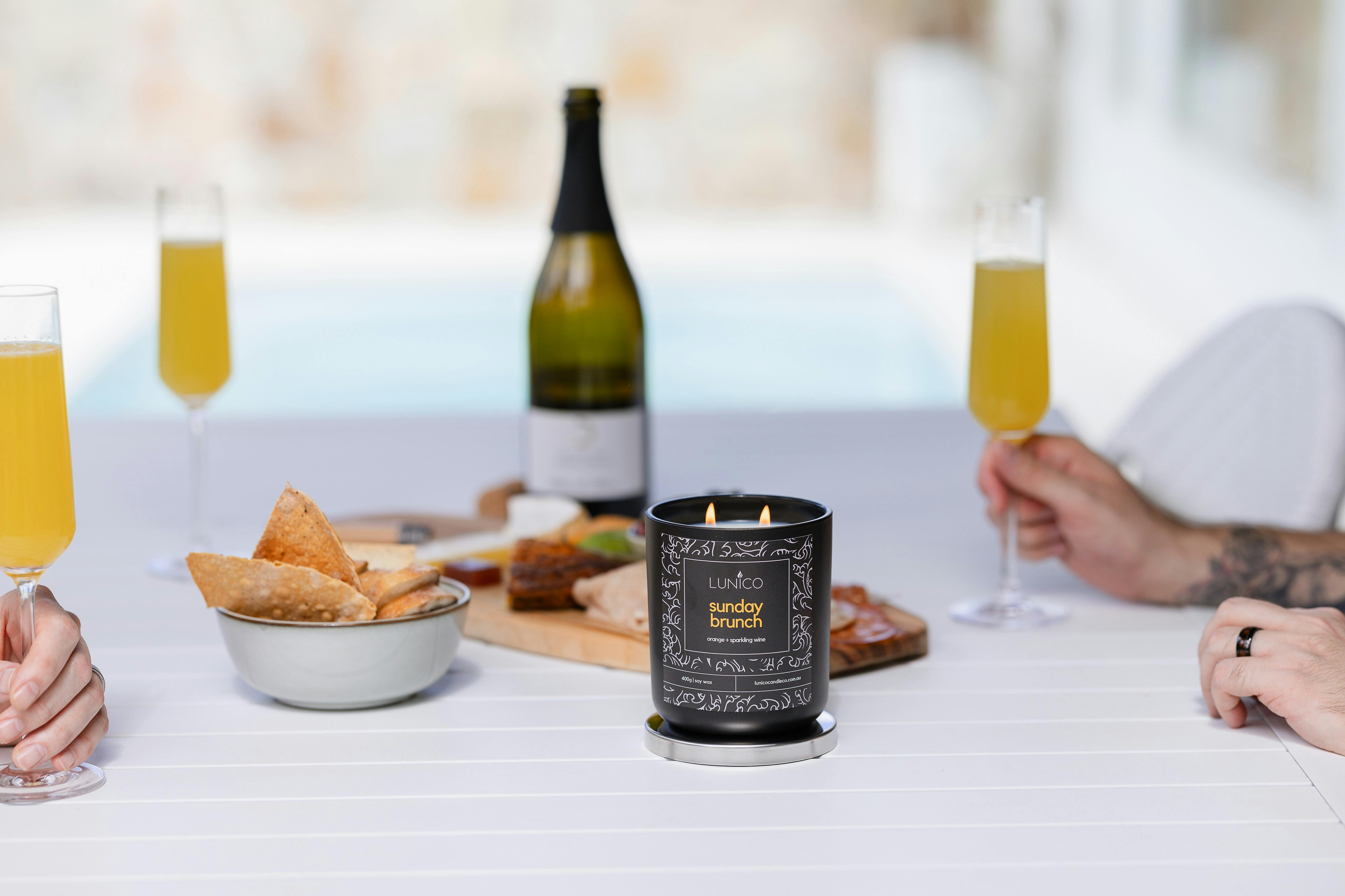 Two men enjoying a grazing platter and mimosas with a candle burning.