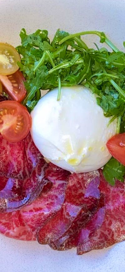 Dish with meat, cheese, tomato and rocket