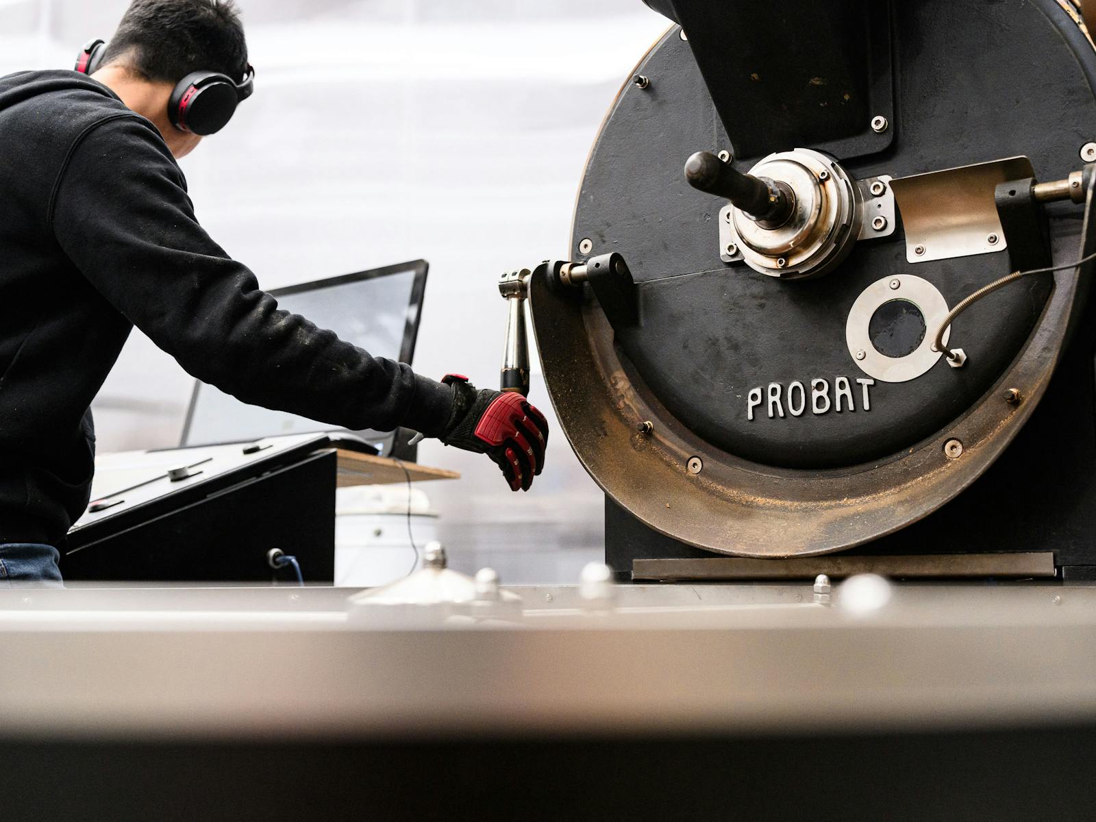 Coffee Roaster roasting coffee on Probat UG22 whilst looking at computer screen.