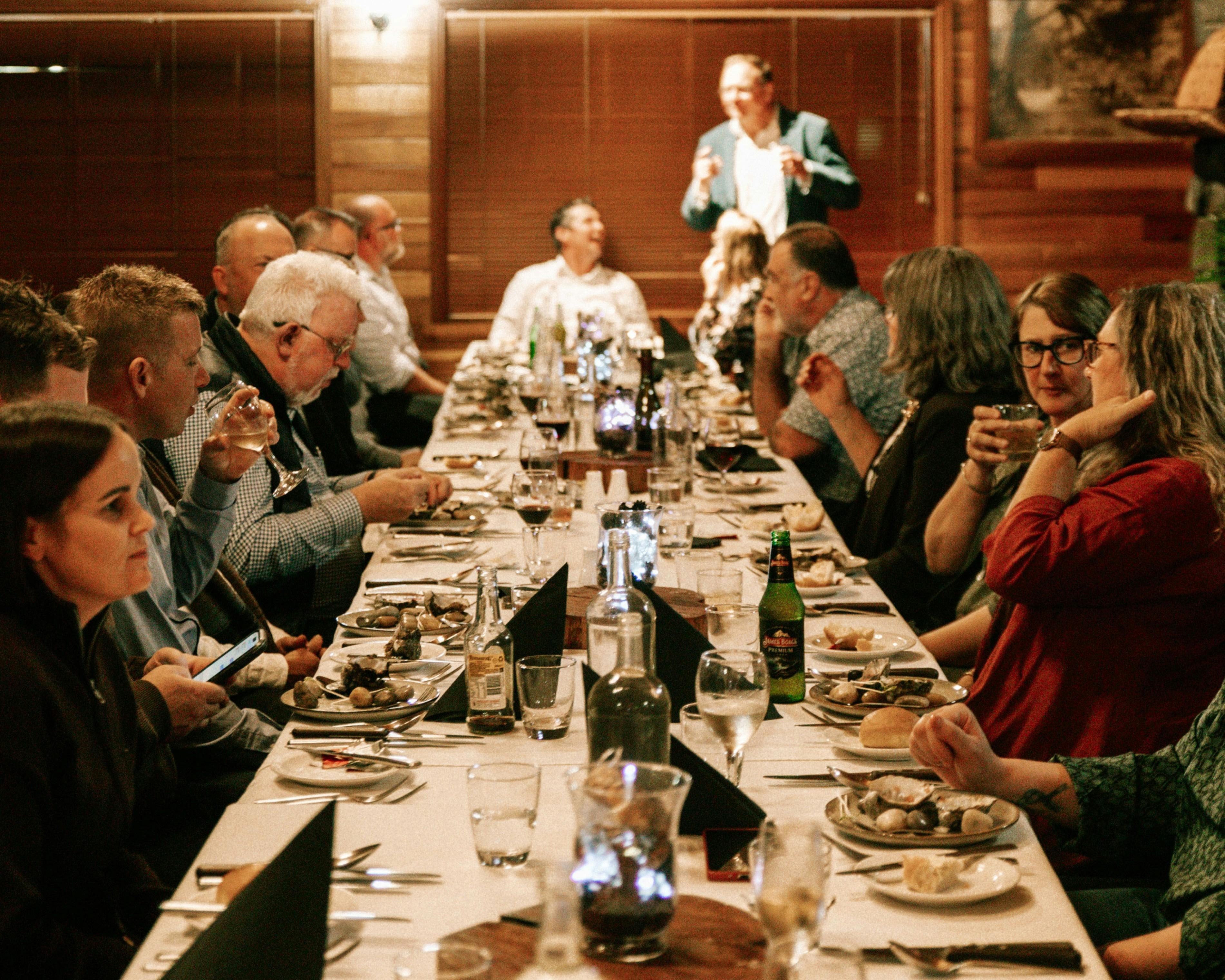 Long table of people eating, low lighting