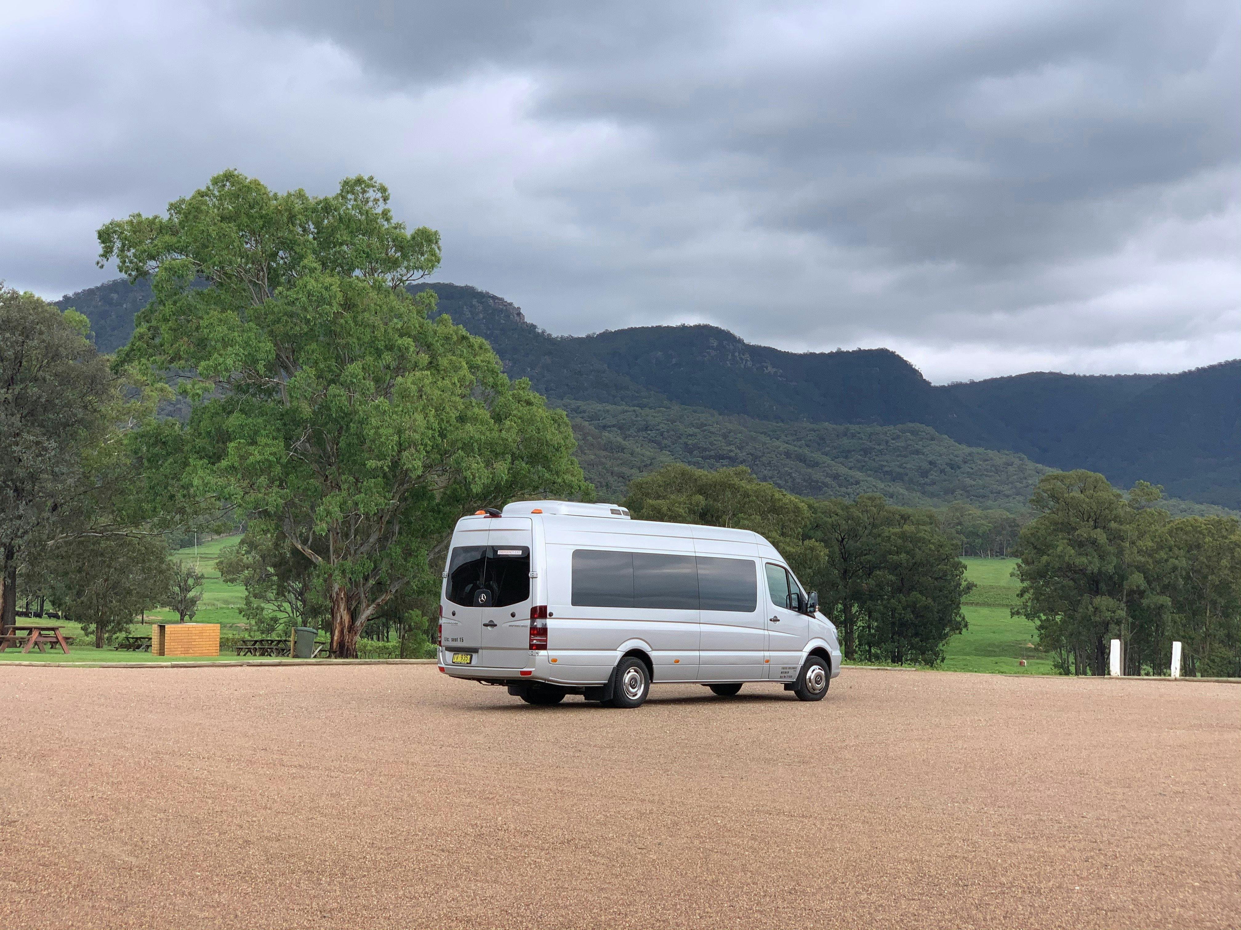 A silver Mercedes Mini-Coach style Van with the Hunter Valley mountains in the background