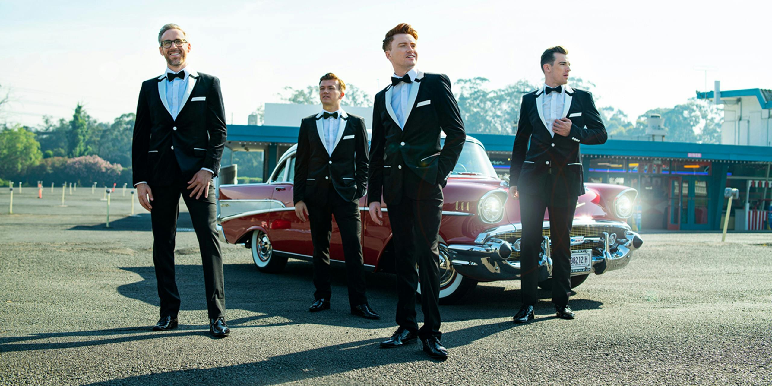 Men in suits in front of red classic car