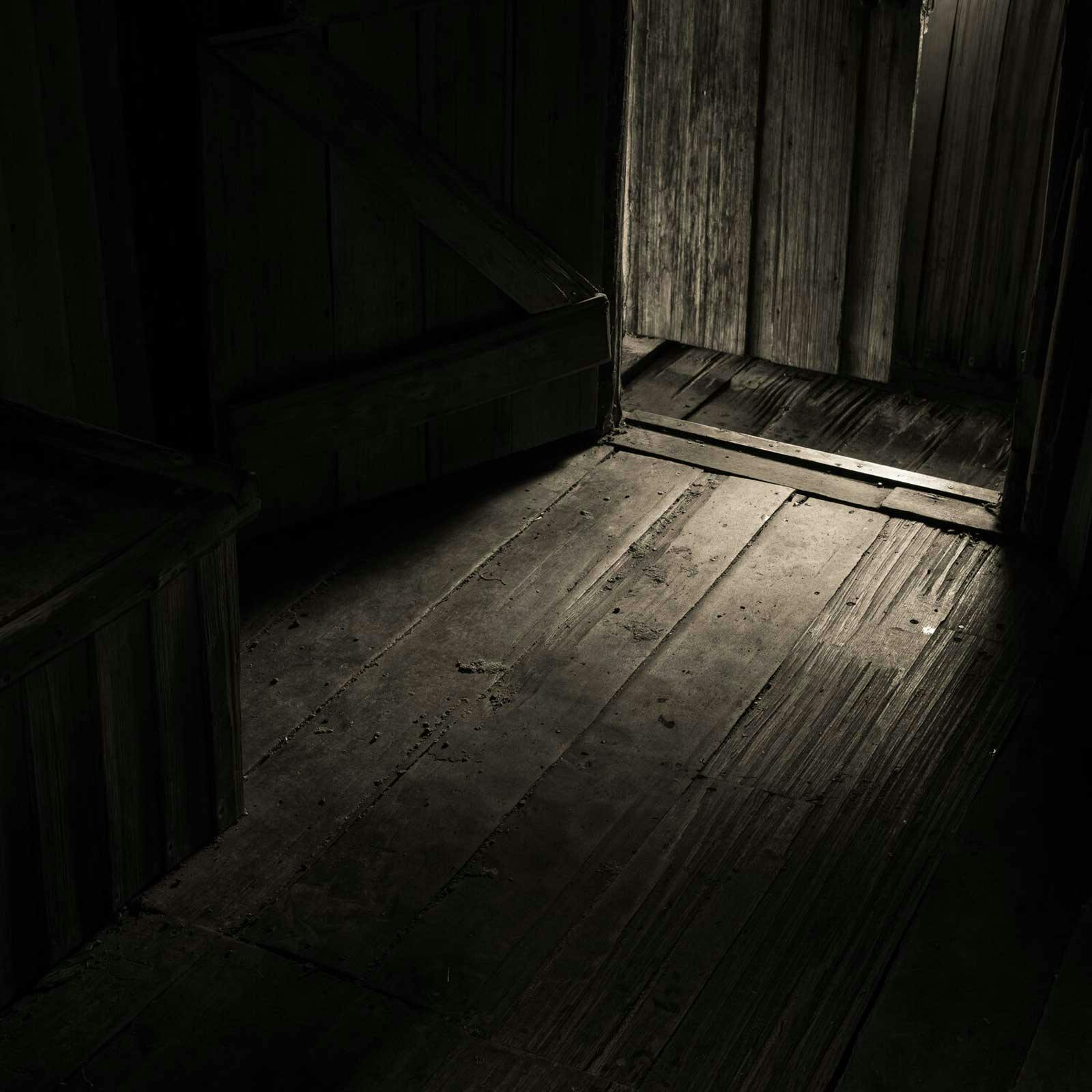 Sepia photograph of light filtering through a doorway capturing the texture of the wood floor