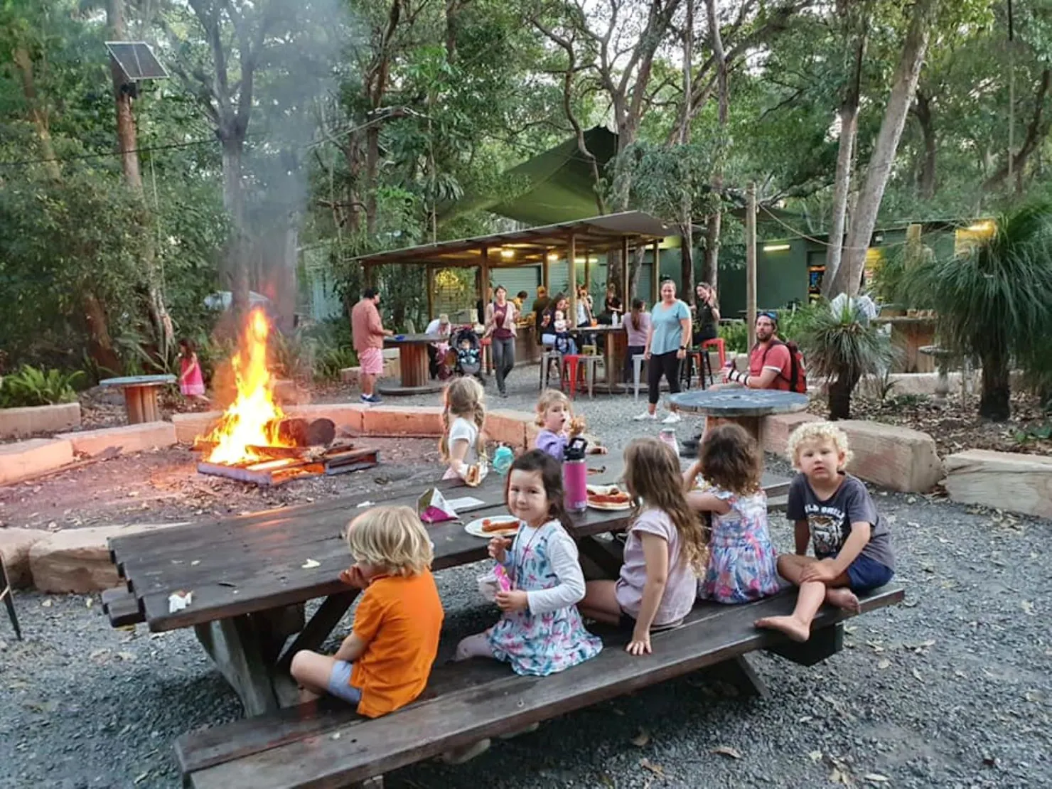 Kids sitting at a campsite on a bench