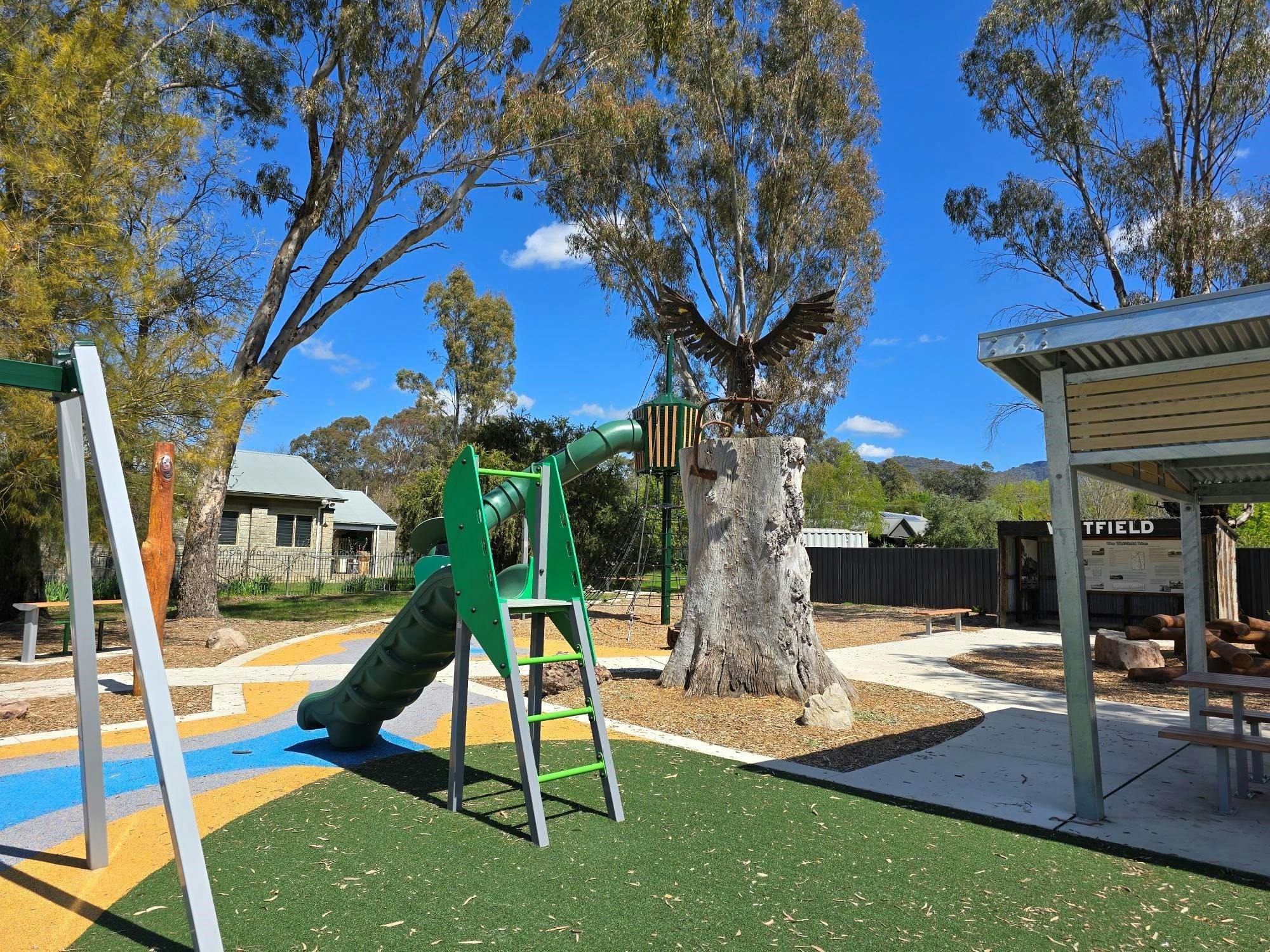 Small slide placed on a green surface with a wedge tailed eagle sculpture in the background