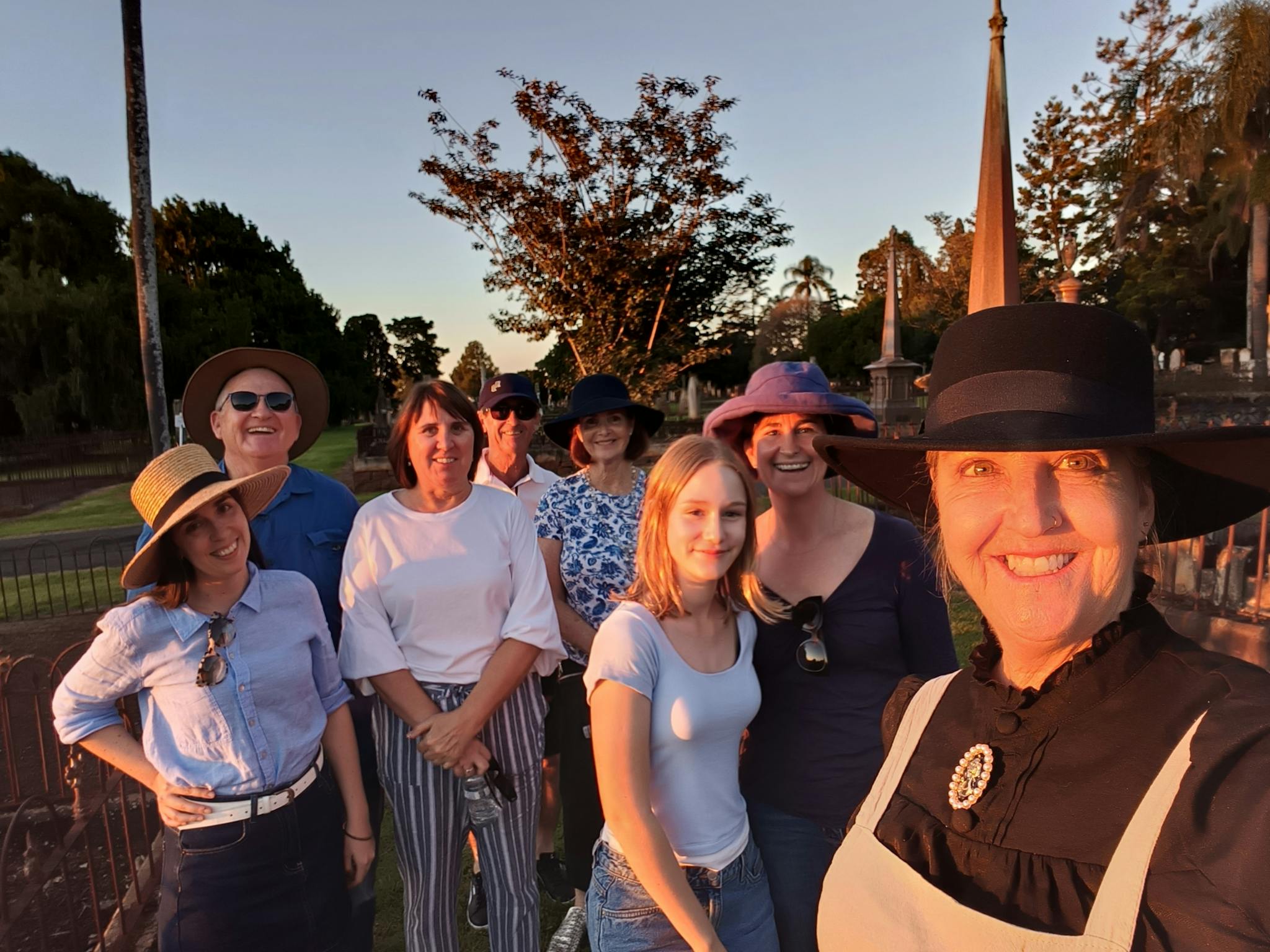 A group of smiling people with a graves in the background