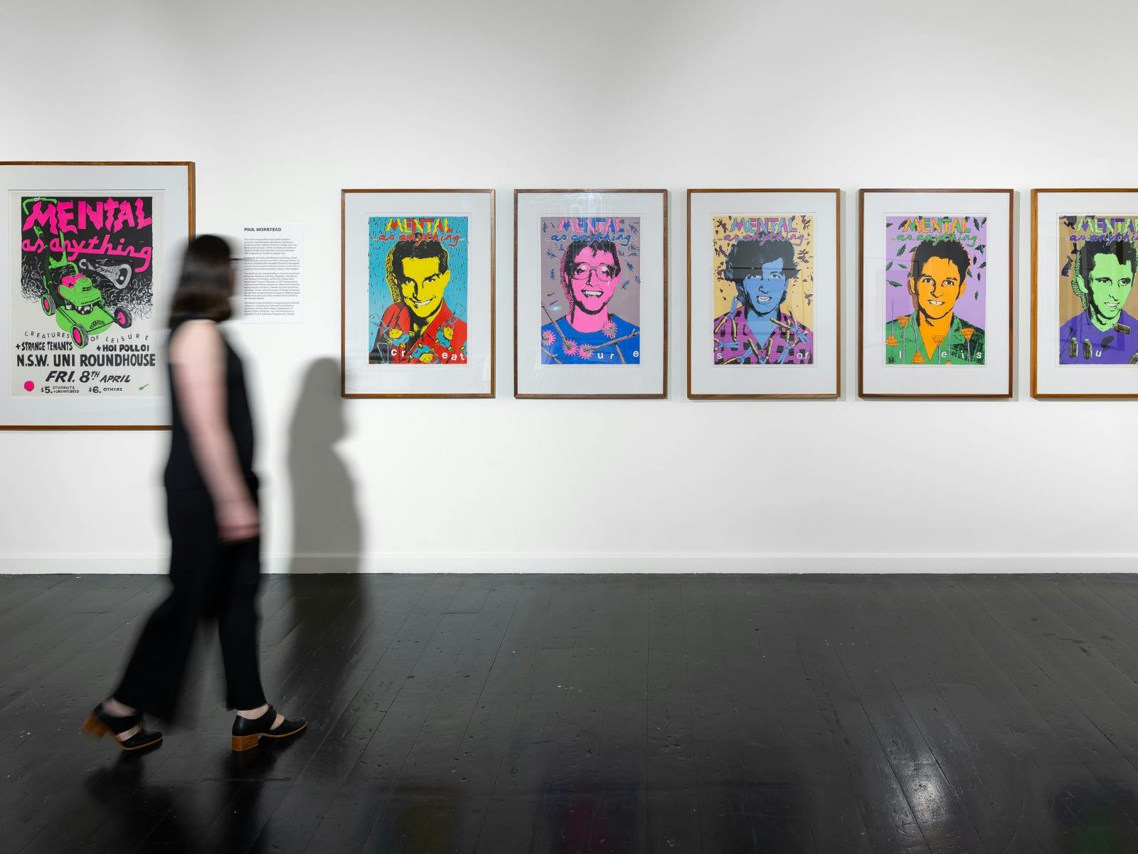 A woman walks in front of colourful artworks in an art gallery
