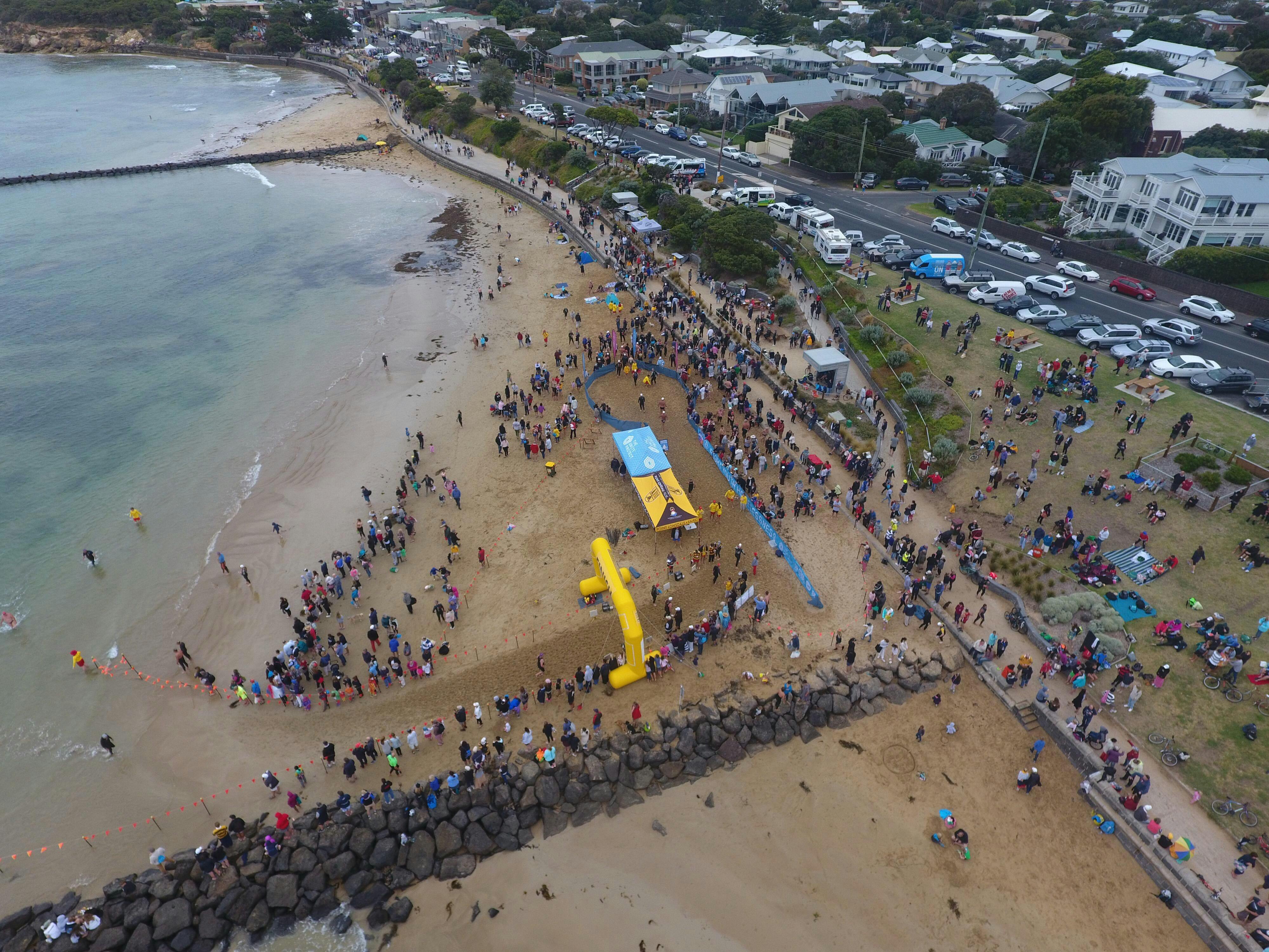 Drone shot of finish line arch on beach with spectatorsP