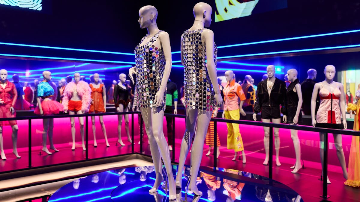 Two mannequins dressed in reflective mirror ball sequin dresses in a night club scene.