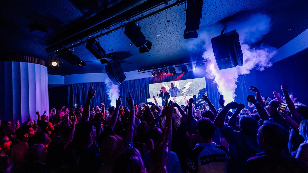 people dancing in front a stage where a woman is performing