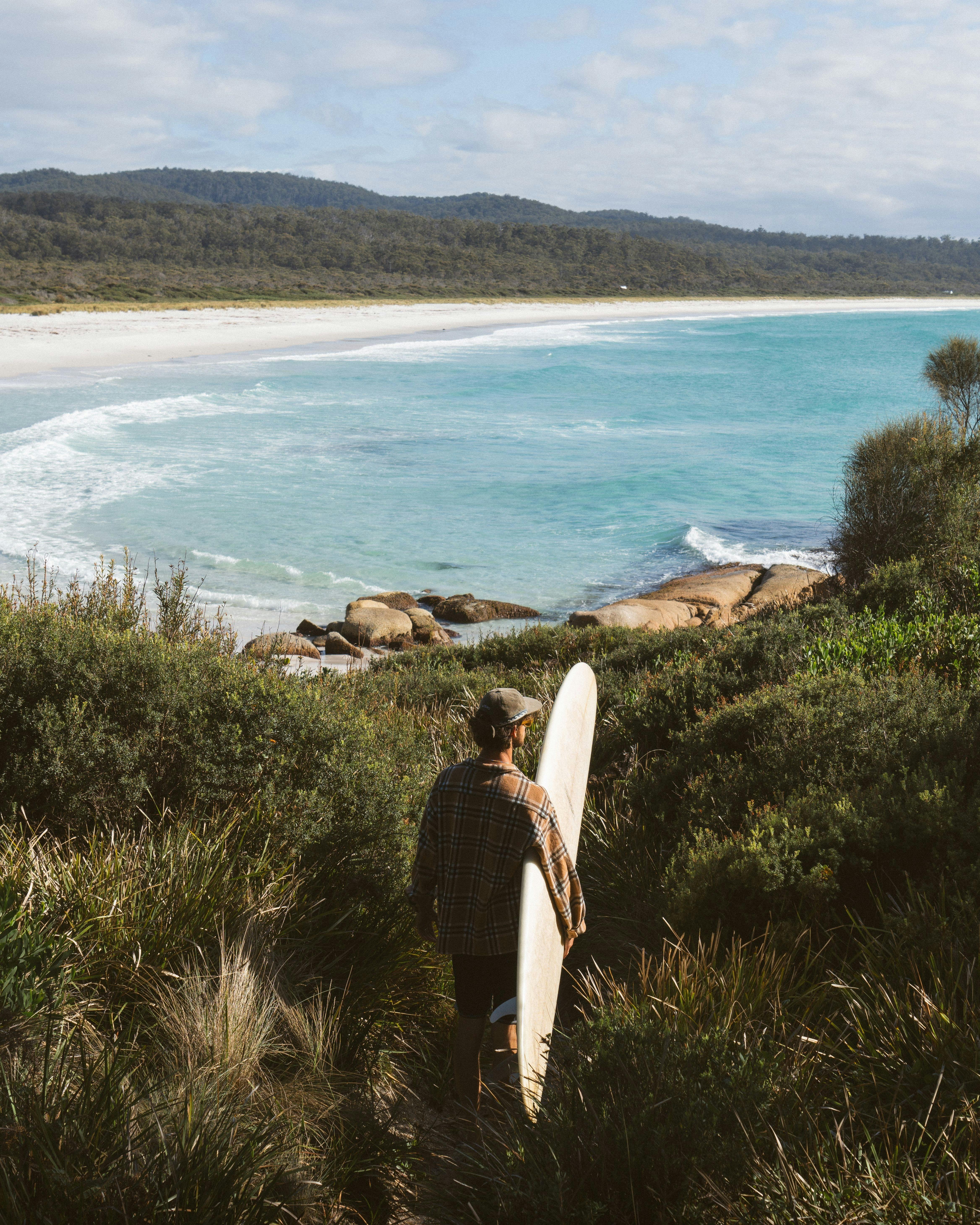 Surfer walking to the waves at Binalong Bay on Tasmania’s East Coast