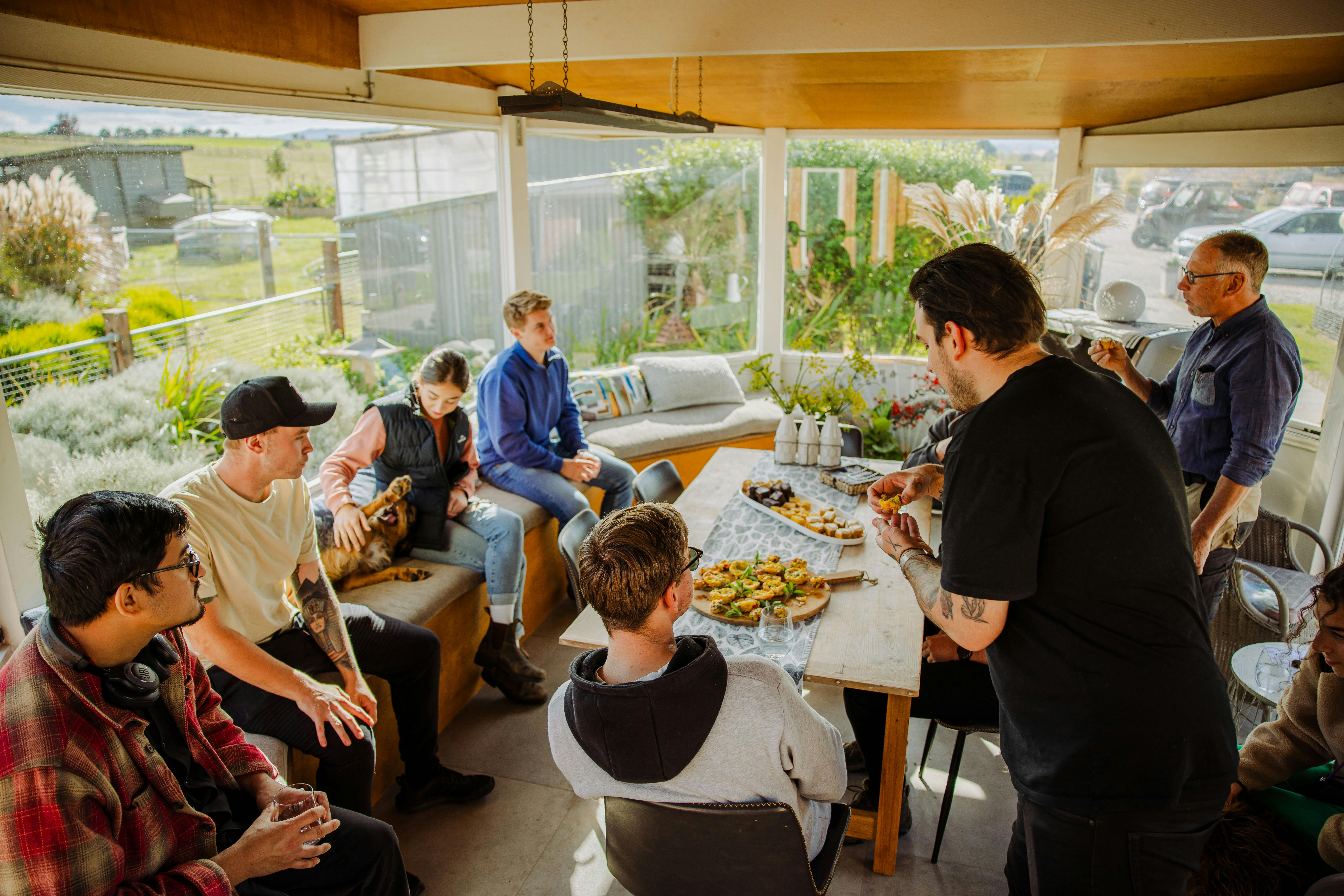 A large group gathers around a long table of shared food at Mudbar Farm.