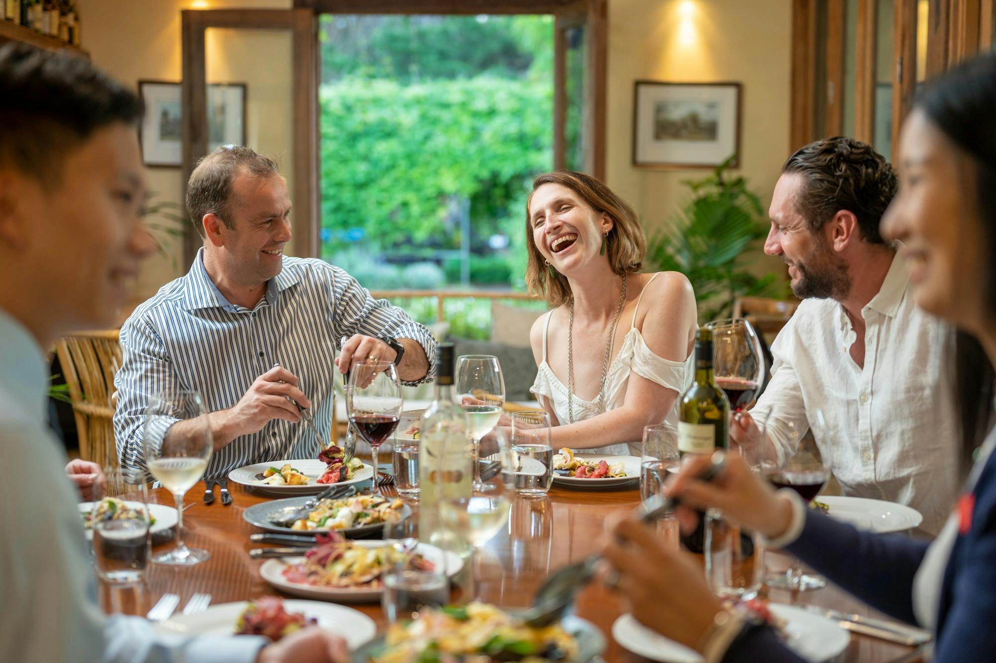 5 people talking and laughing while enjoying a meal.