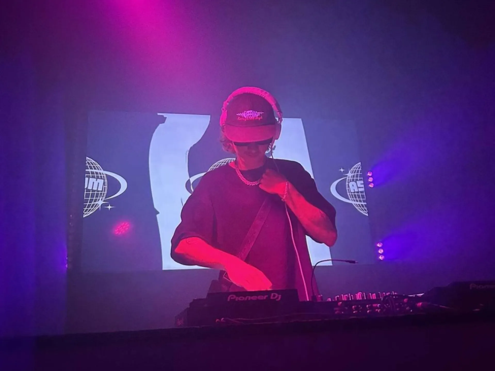 A DJ on stage with pink and purple lights