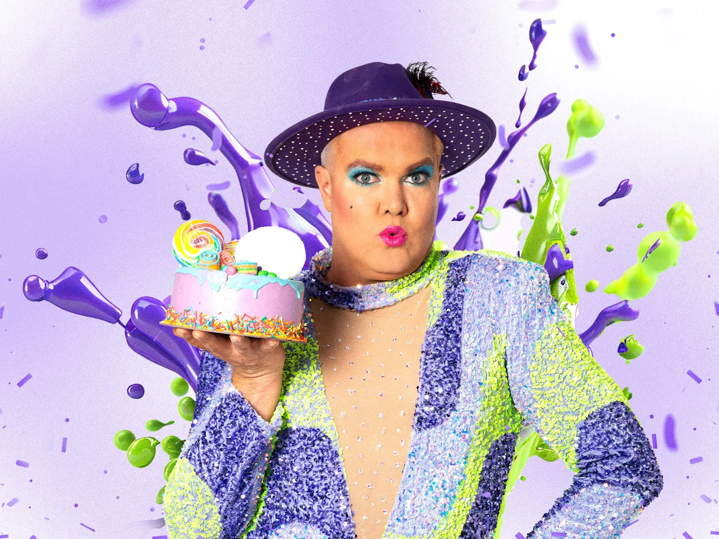 A middle aged man wearing heavy makeup and a sparkling purple outfit holding a birthday cake.