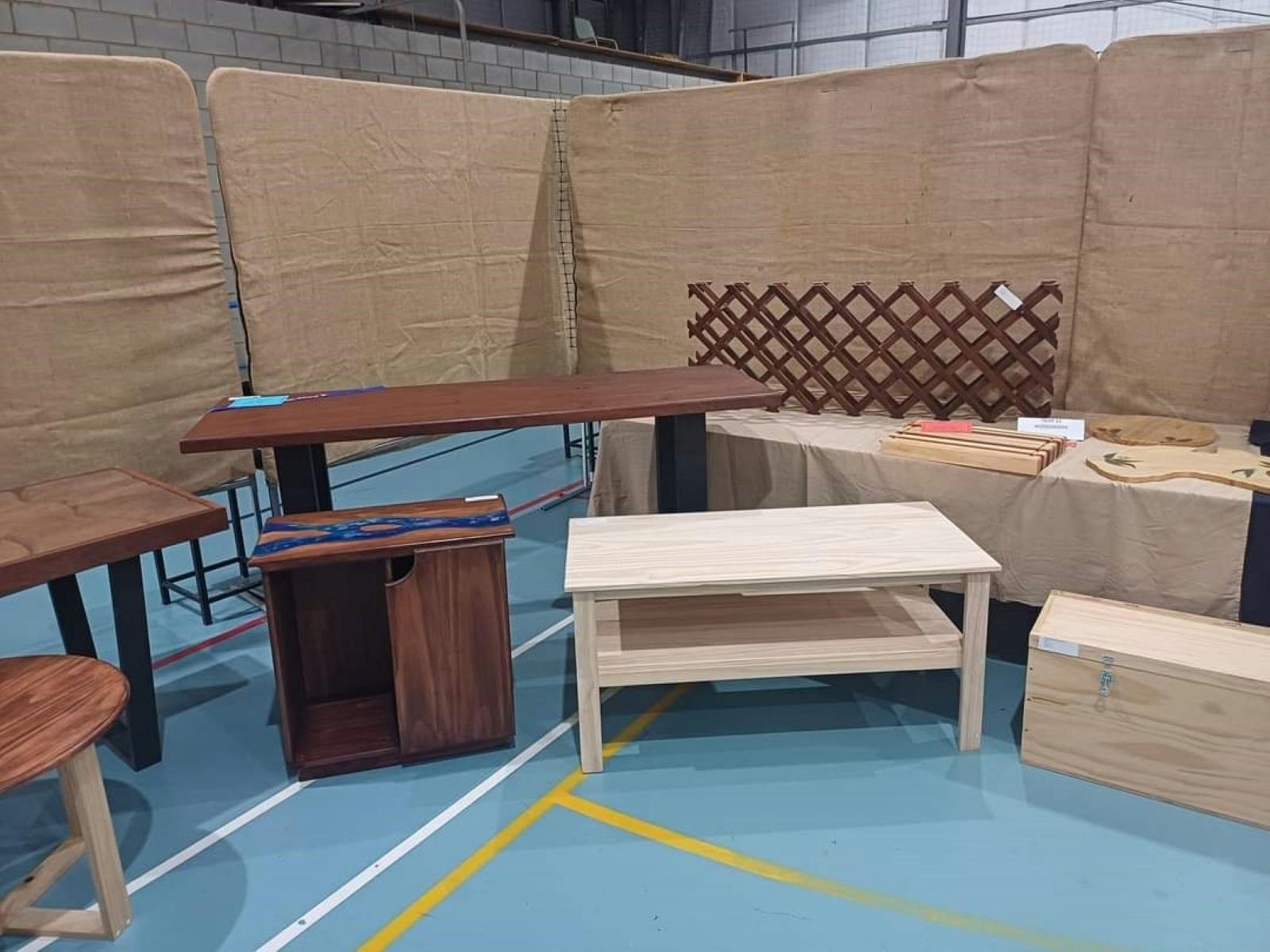 Photo shows various hand made wooden objects ranging from coffee tables, desks, and stools.