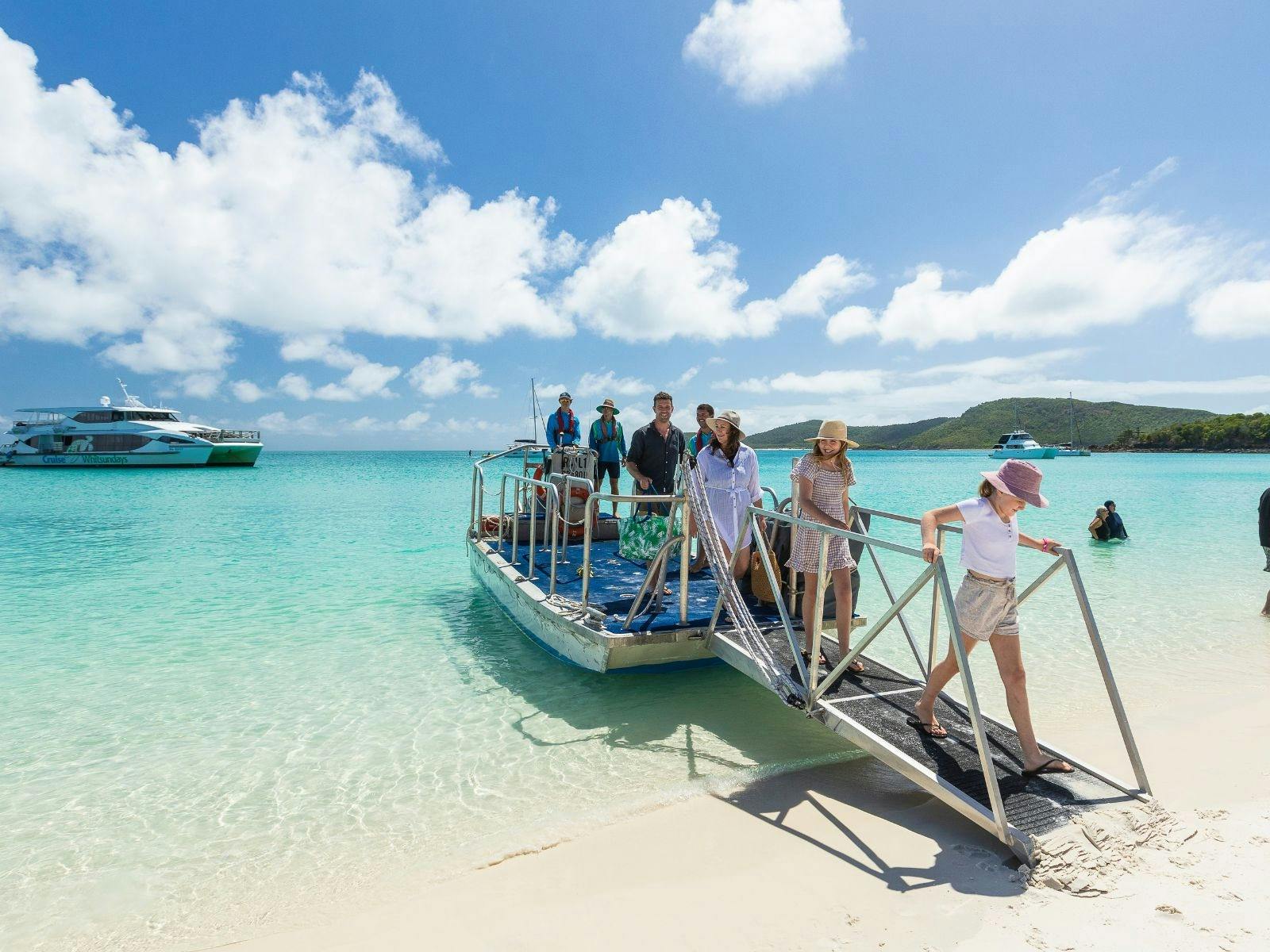A family stepping off a tender onto the beach