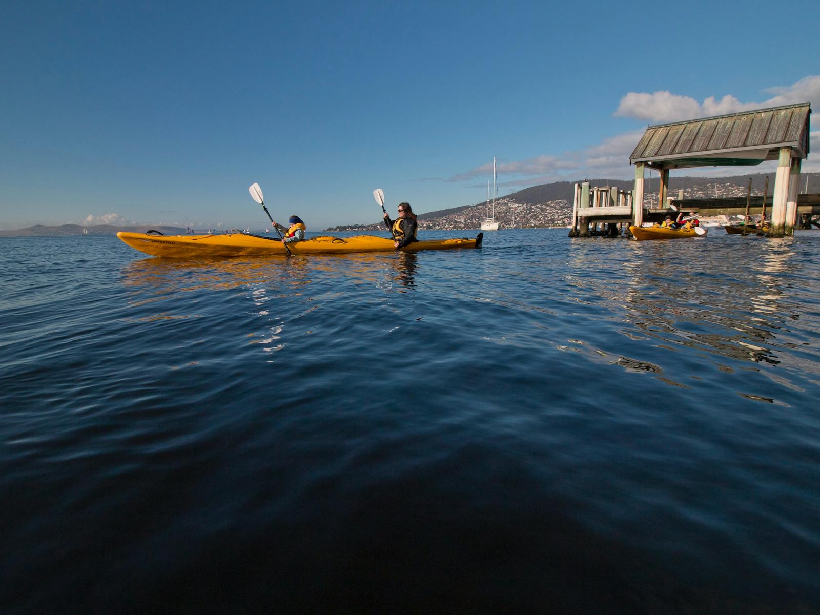 Kayakers paddling under jetties on the Derwent River, Hobart