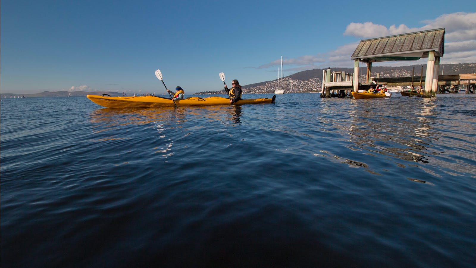 Kayakers paddling under jetties on the Derwent River, Hobart