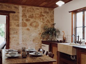 Rustic kitchen and dining area with original limestone walls at 1856 Cottage in Robe South Australia