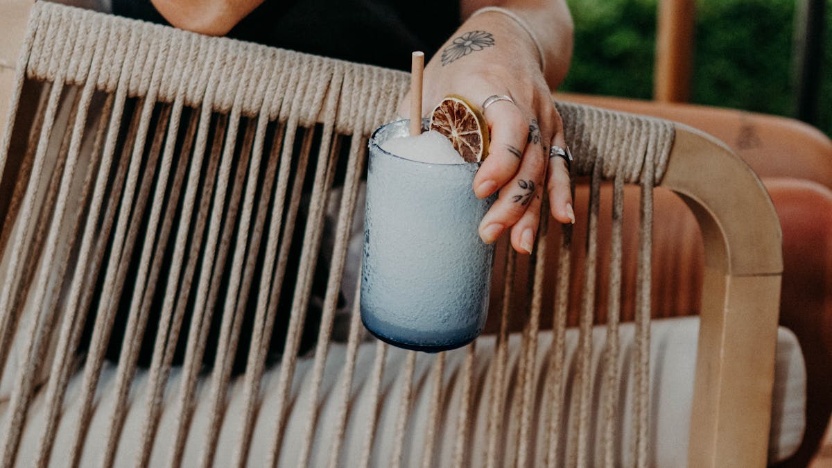 A woman enjoying a margarita while sitting on a chair, looking relaxed and content.