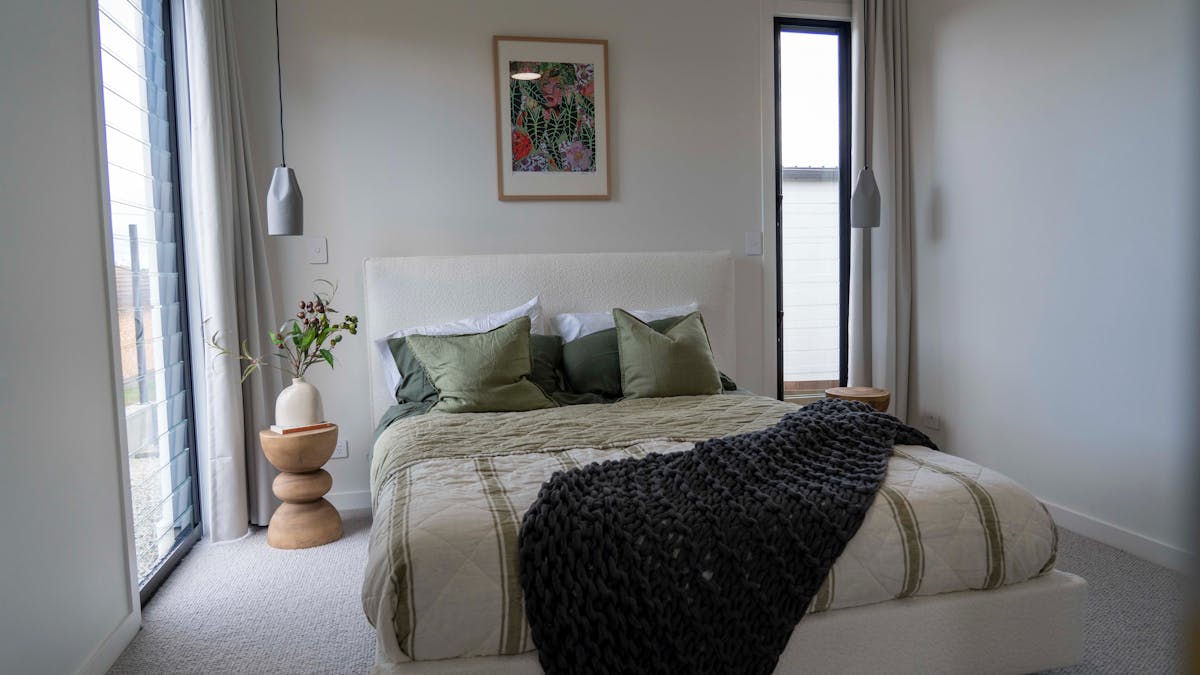 bedroom with plus knit wool carpet, green linen and artwork by Sarah Hickey artist.
