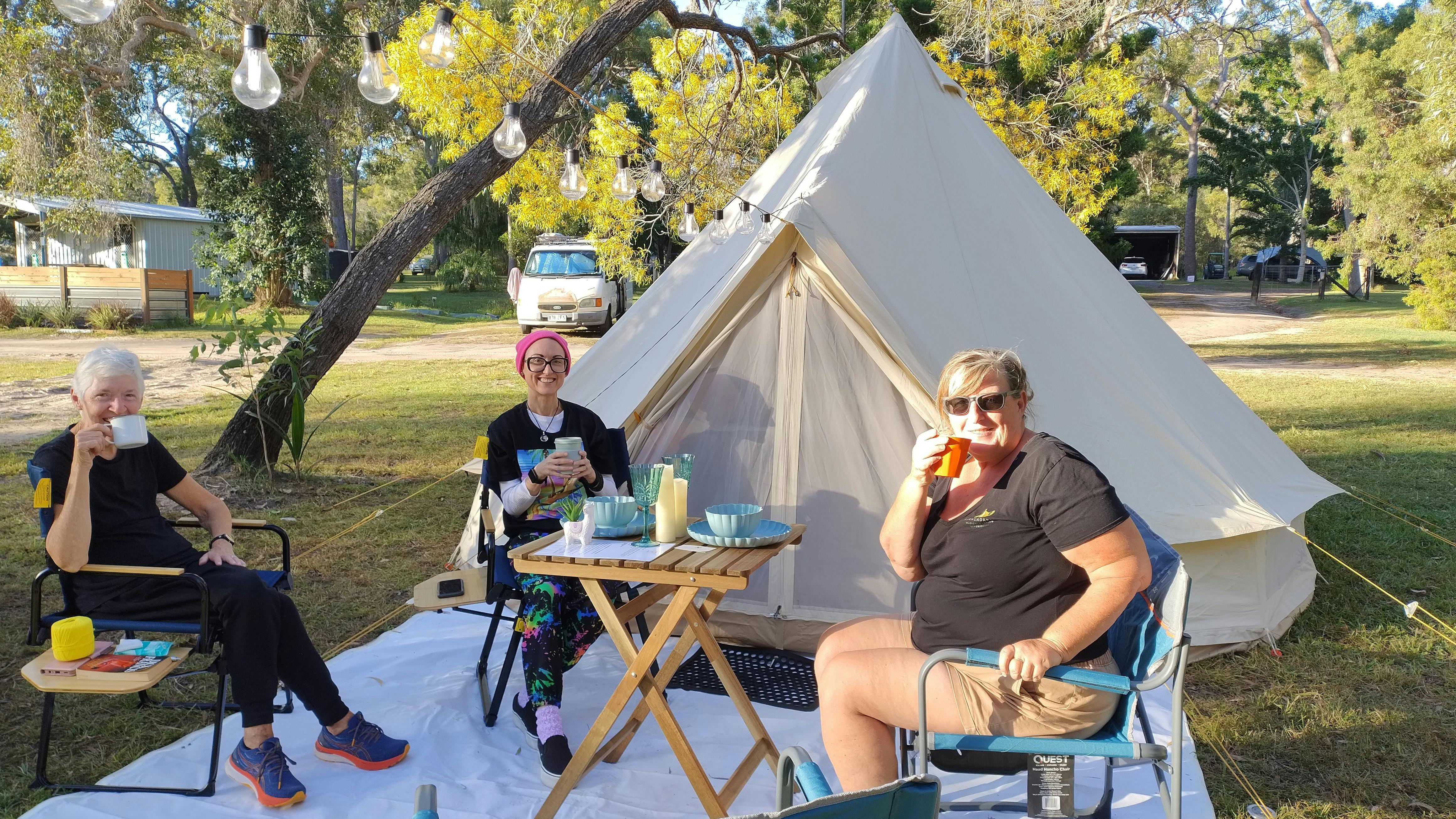 Friends enjoying afternoon tea in front of a bell tent