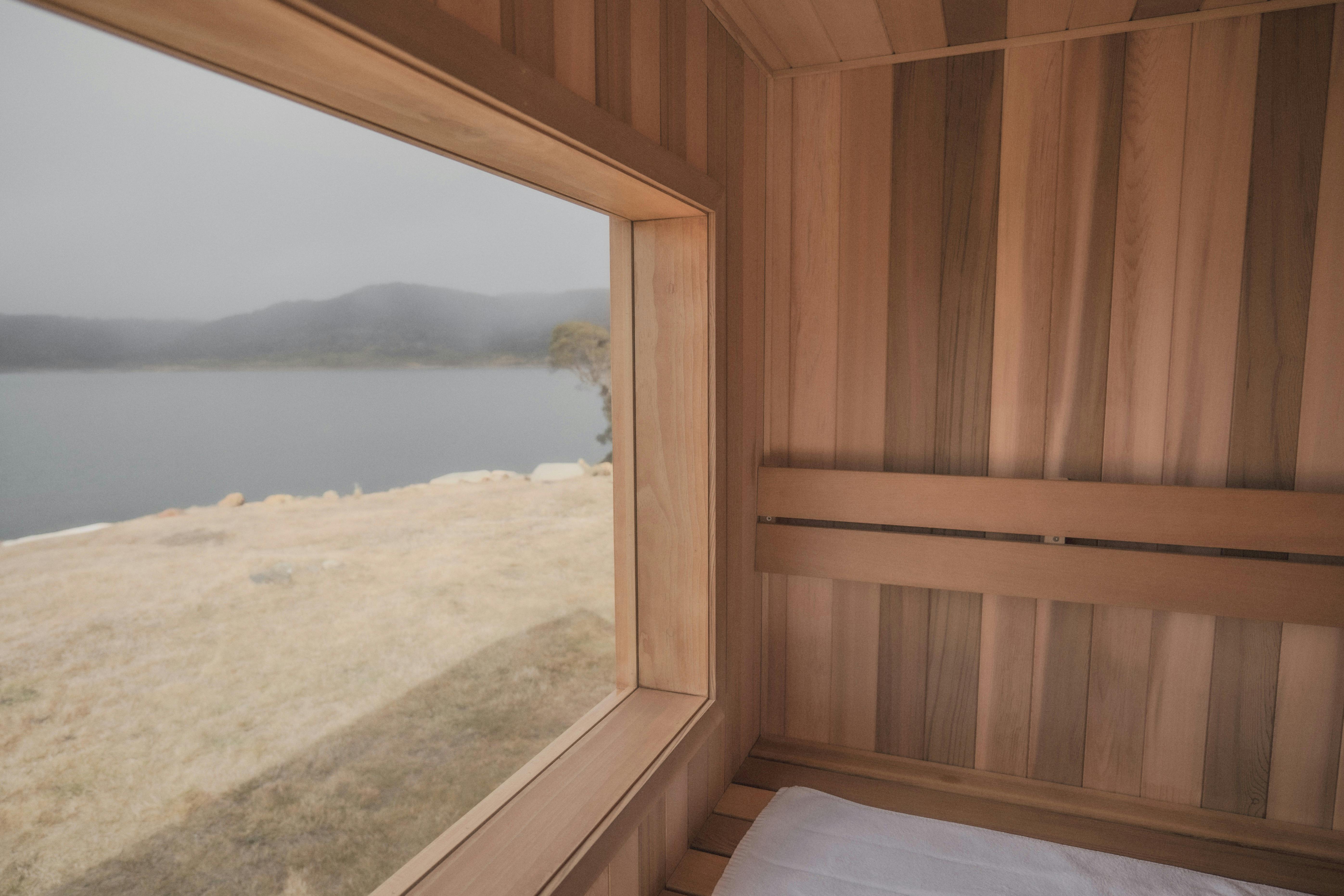 Interior view shot of Finnish style cedar sauna with view of nature and lake on a cloudy day