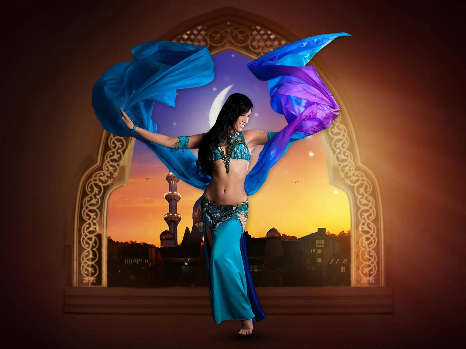 A belly dancer in vibrant attire performs with flowing fabric, set against a sunset backdrop.