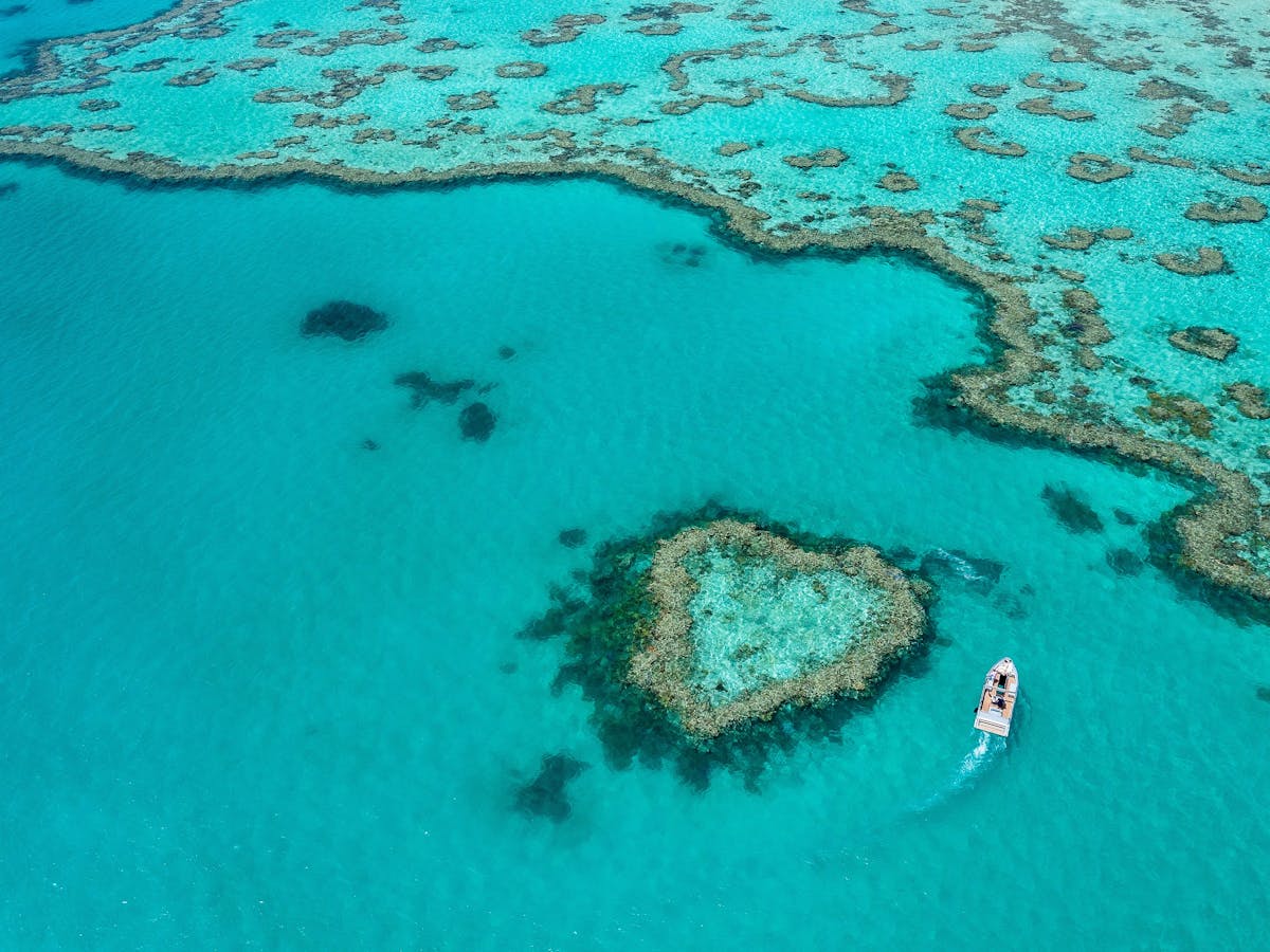 A boat driving around the heart shape reef in turquoise water