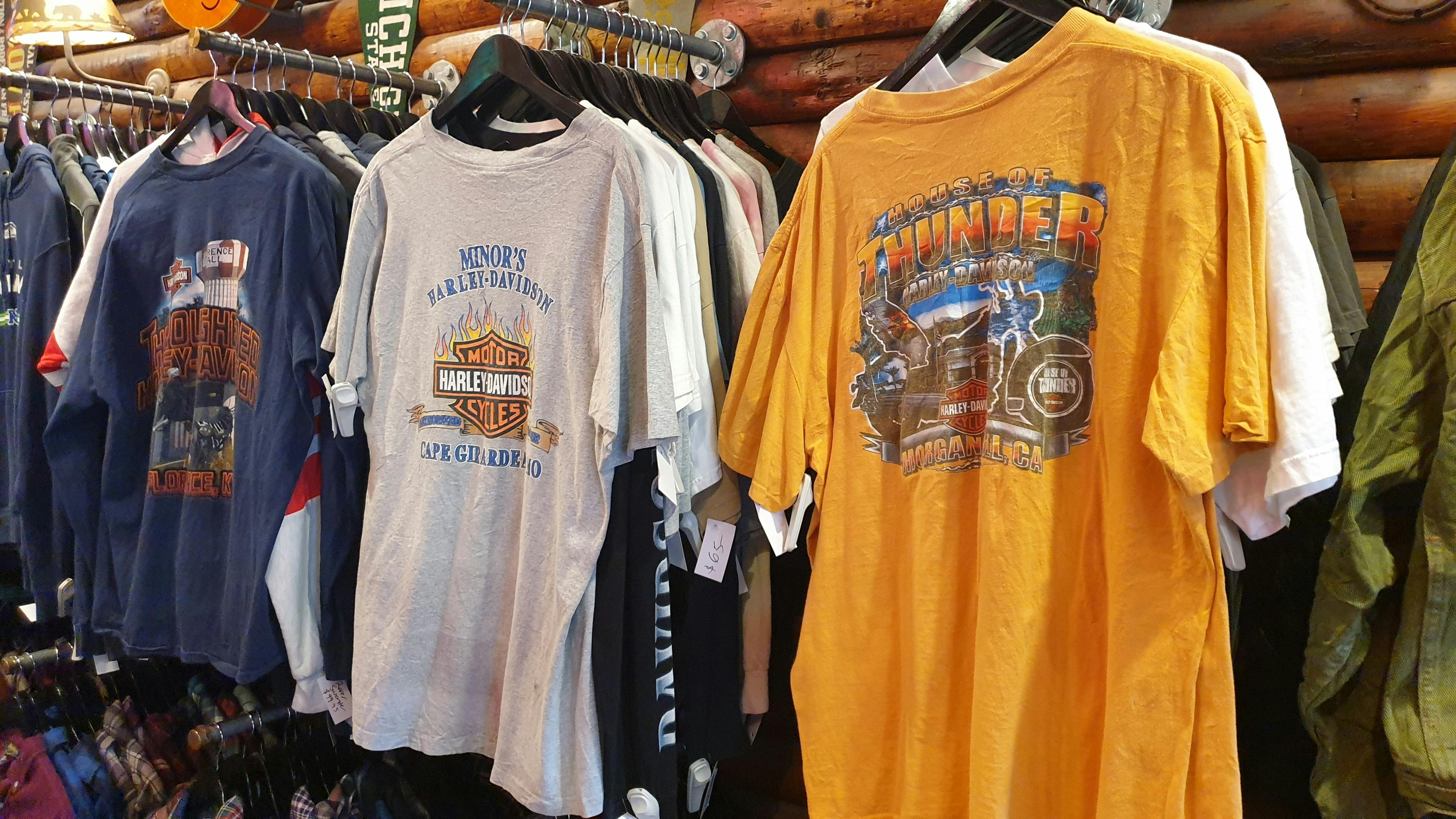 A row of Harley Davidson-printed motorcycle t-shirts hang on a wall.